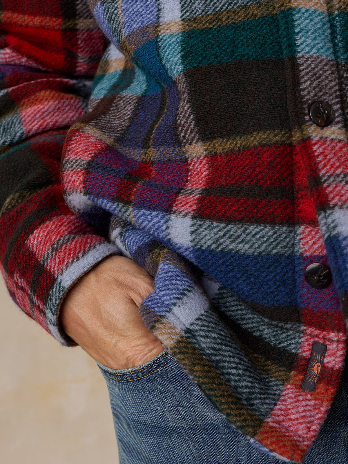 Close up of a man wearing a multicolored plaid jacket and jeans, image 5 of 6