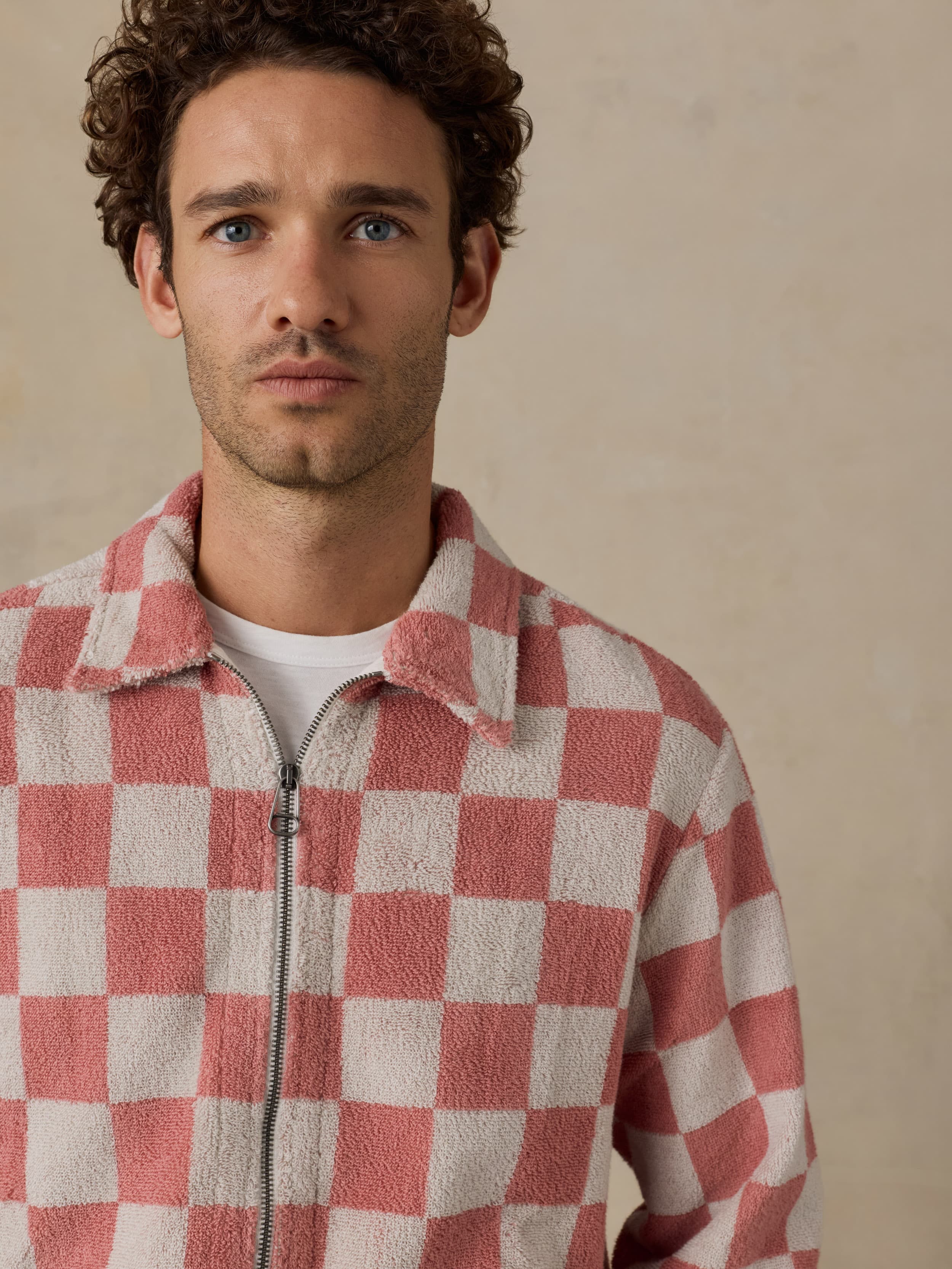 Man wearing a red and white checkered terry jacket against a beige background