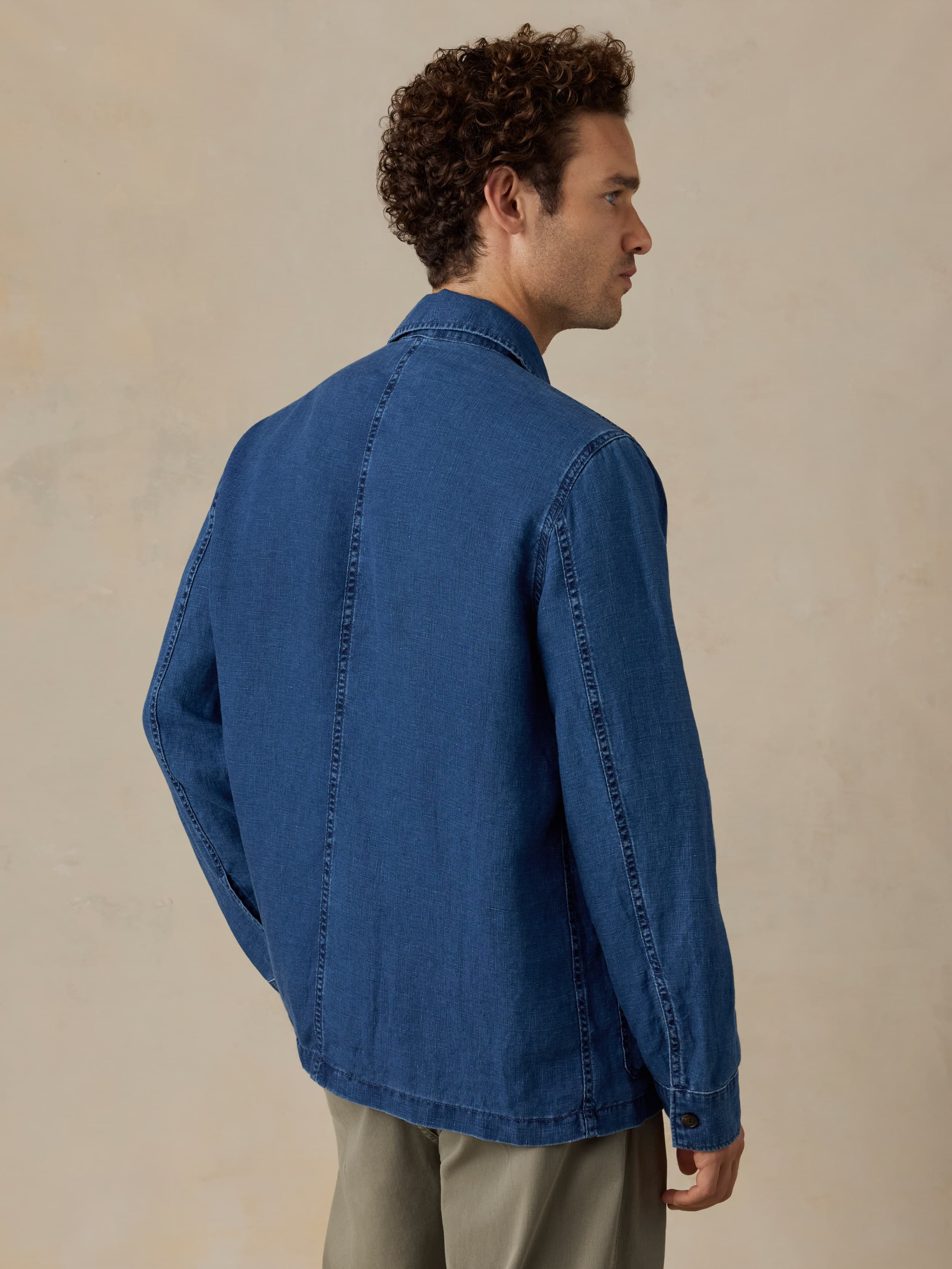 Man wearing a blue denim jacket against a beige background