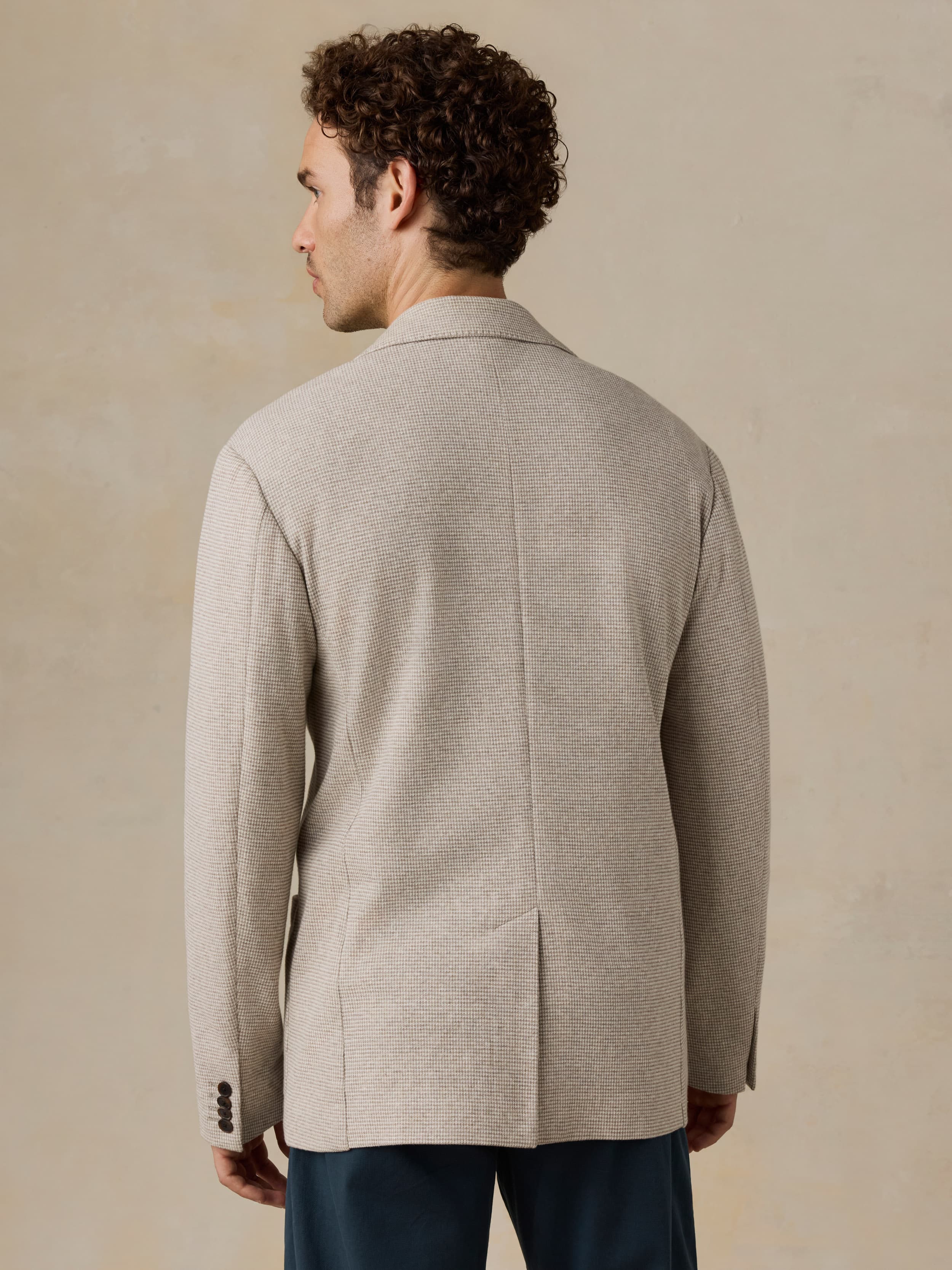 Man wearing a beige blazer against a beige background