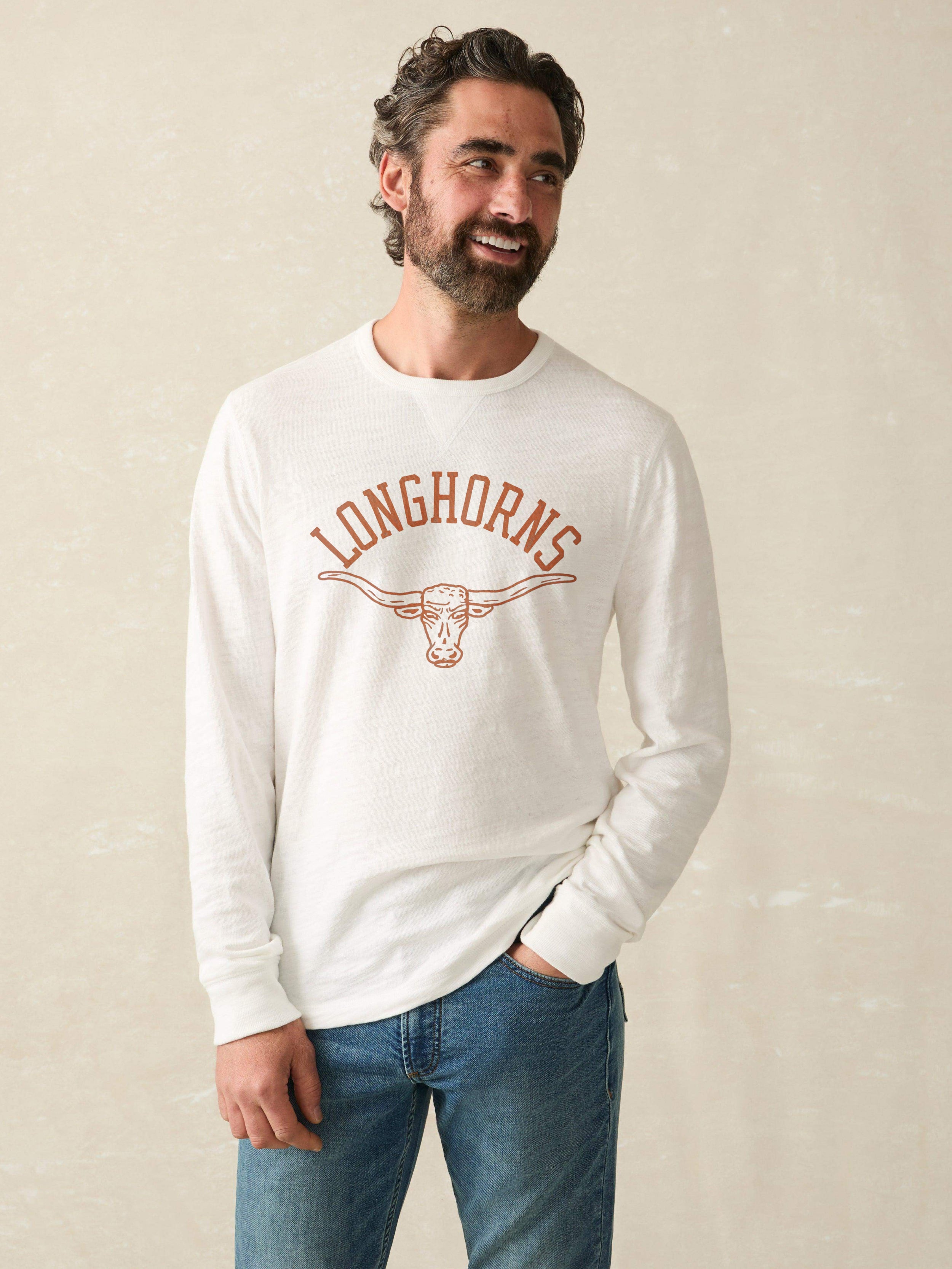 Man wearing a white long-sleeve shirt with University of Texas graphic at the center chest against a beige background