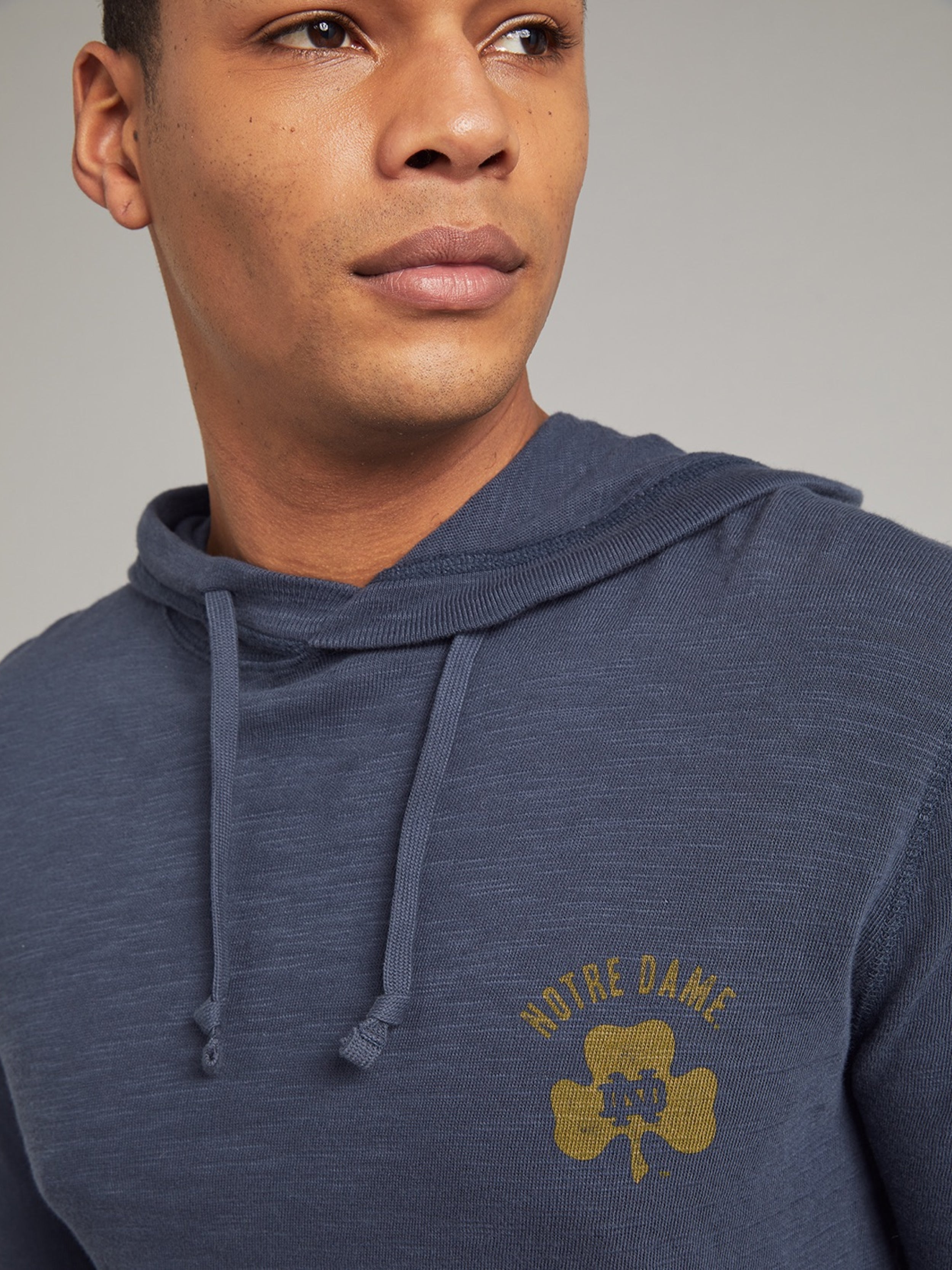 Man wearing a navy hoodie with Notre Dame graphic on the left chest back against a grey background