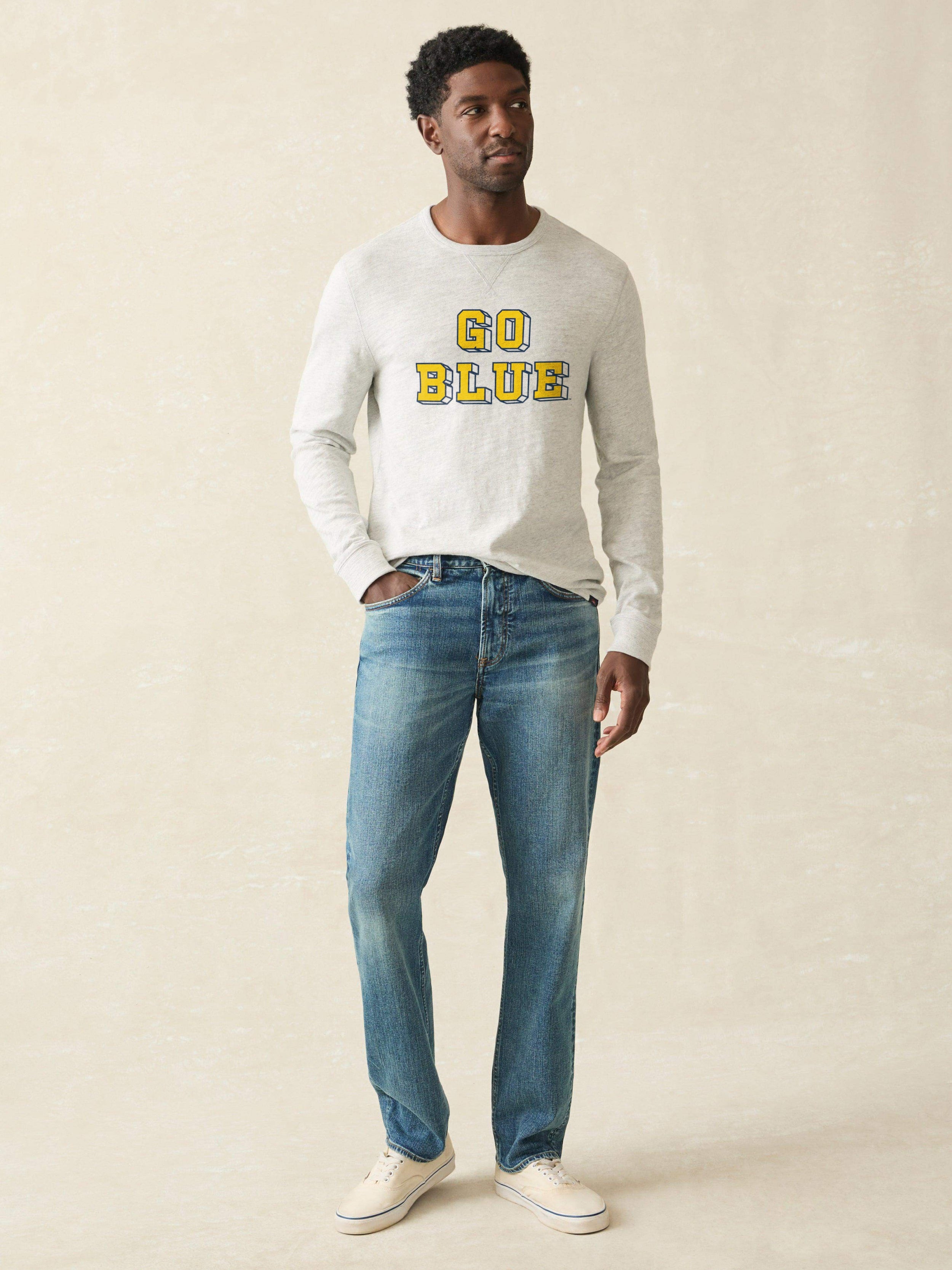 Man wearing a grey sweatshirt with Michigan graphic on the front against a beige background