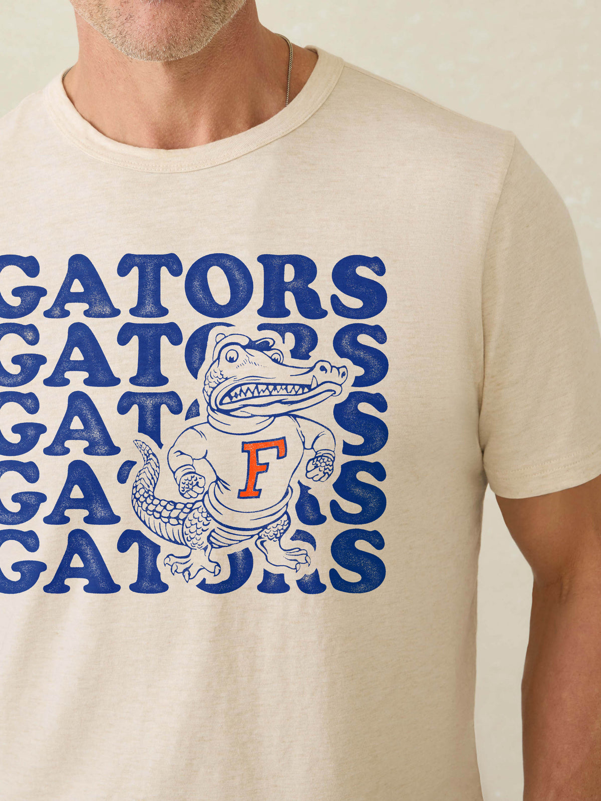 Man wearing a white short-sleeve t-shirt with University of Florida graphic at the center front against a beige background, image 2 of 3