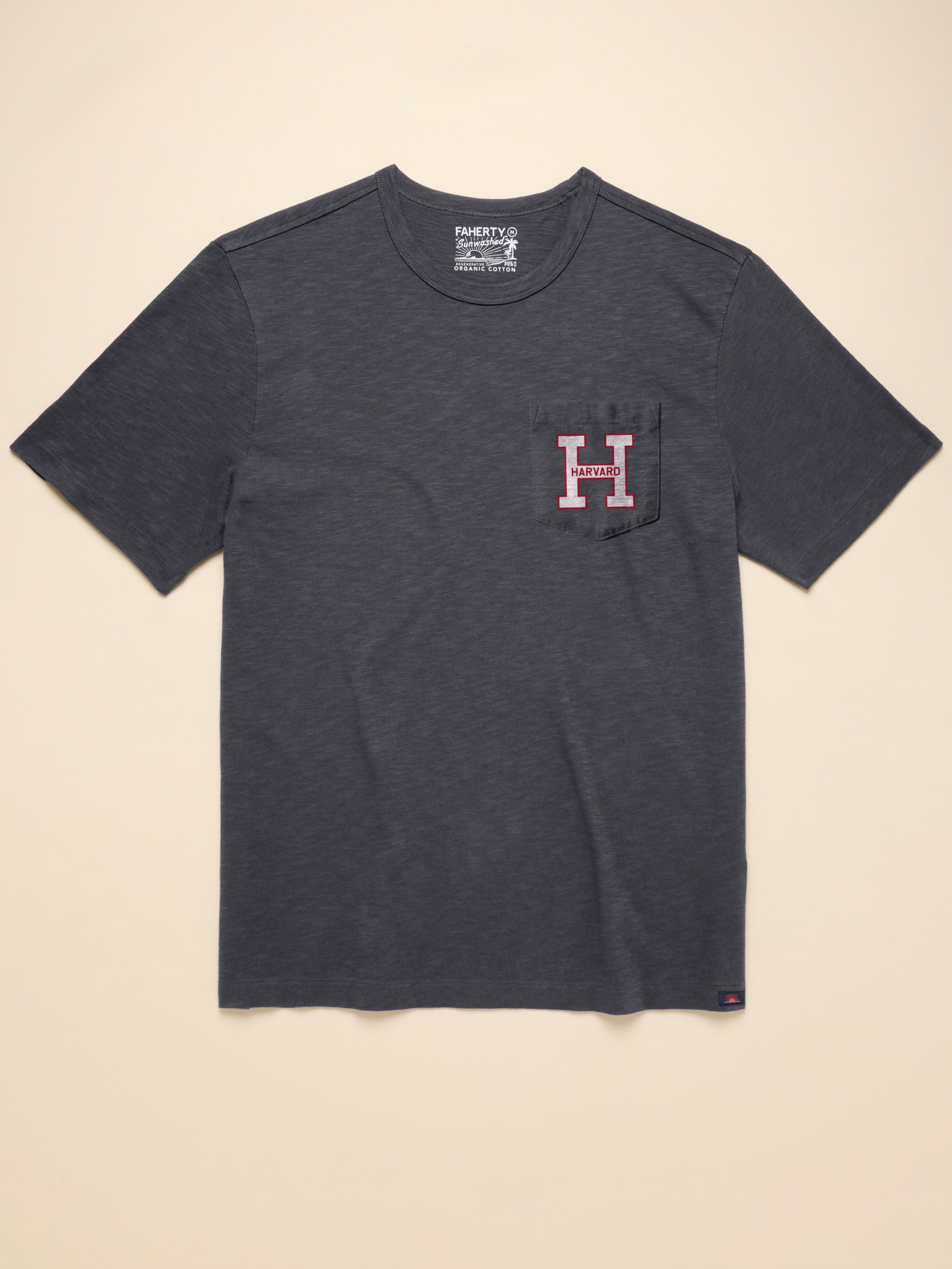 Gray t-shirt with Harvard graphic on front left chest pocket against a beige background