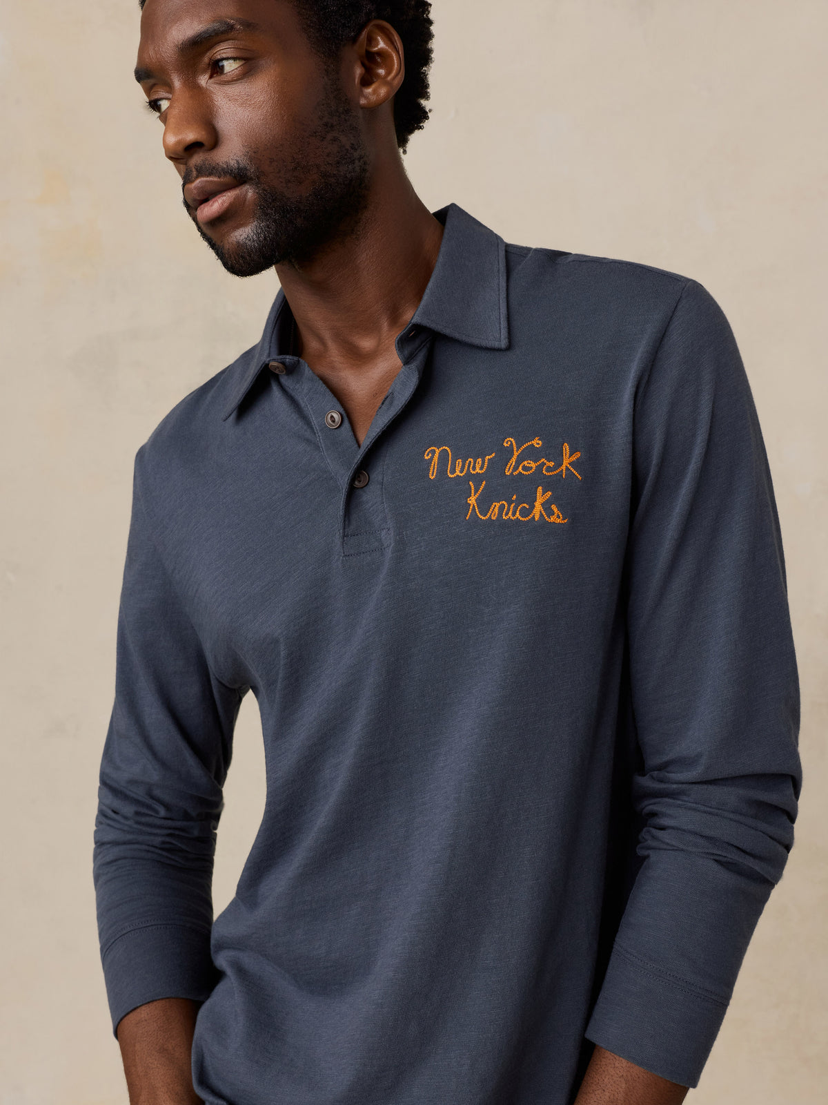 A man wearing a blue NY Knicks polo shirt, image 3 of 8