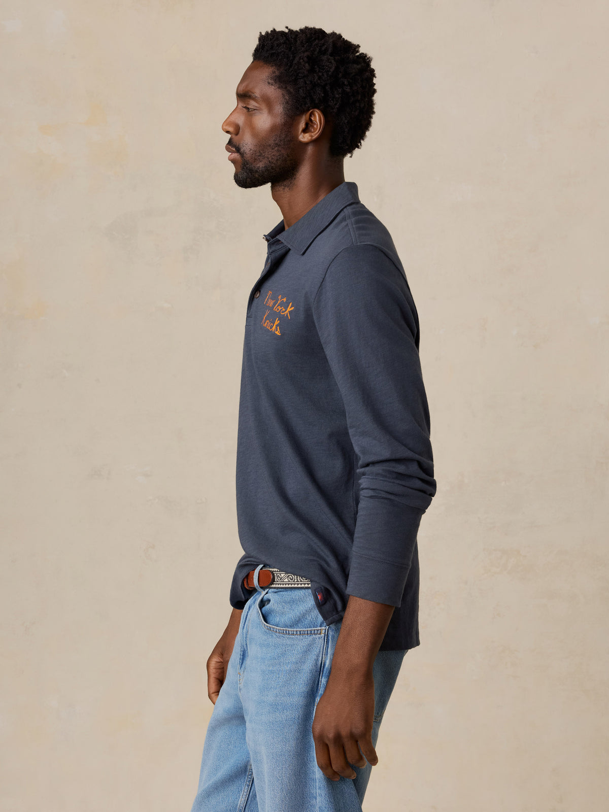 A man wearing a blue NY Knicks polo shirt, image 6 of 8