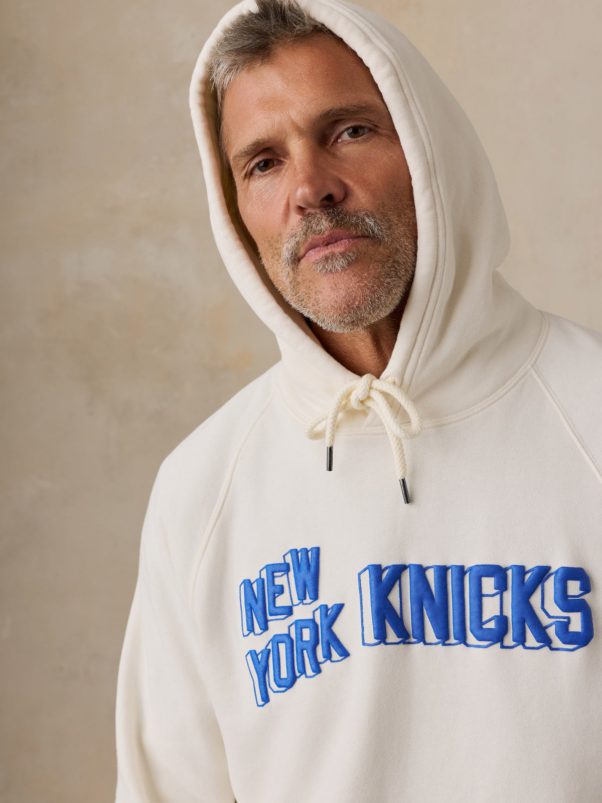 Close up of a man wearing a white NY Knicks hoodie, image 4 of 6