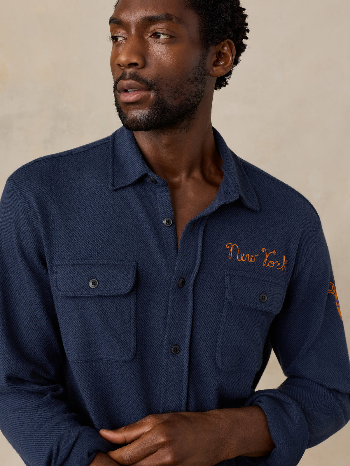 Close up of a man wearing a navy NY Knicks button up shirt, image 4 of 6