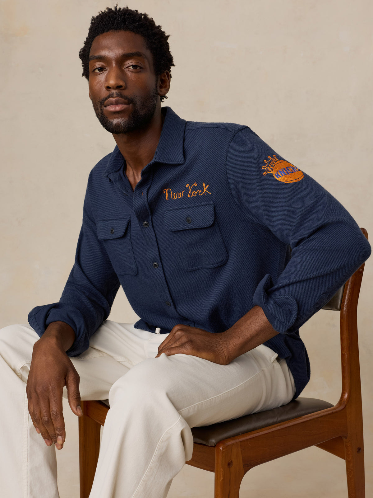 A man wearing a navy NY Knicks button up shirt, image 3 of 6