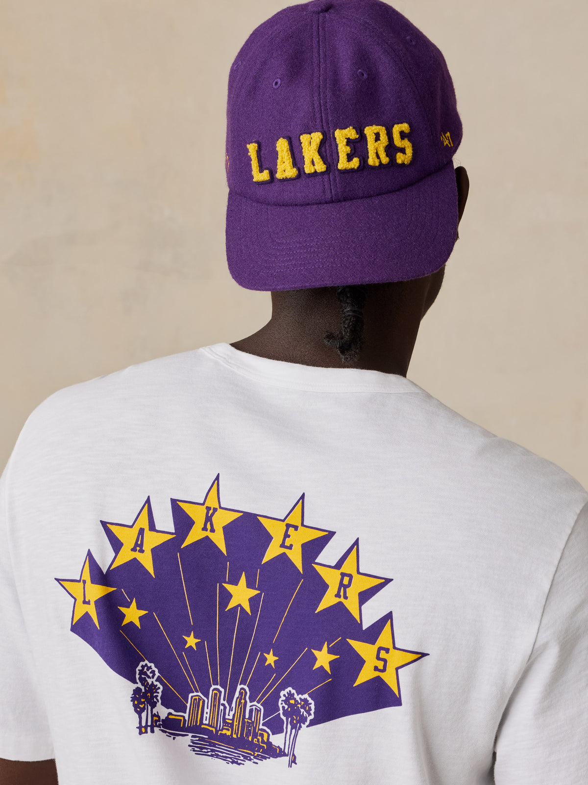 A man viewed from behind wearing a white LA Lakers tee and hat, image 3 of 6