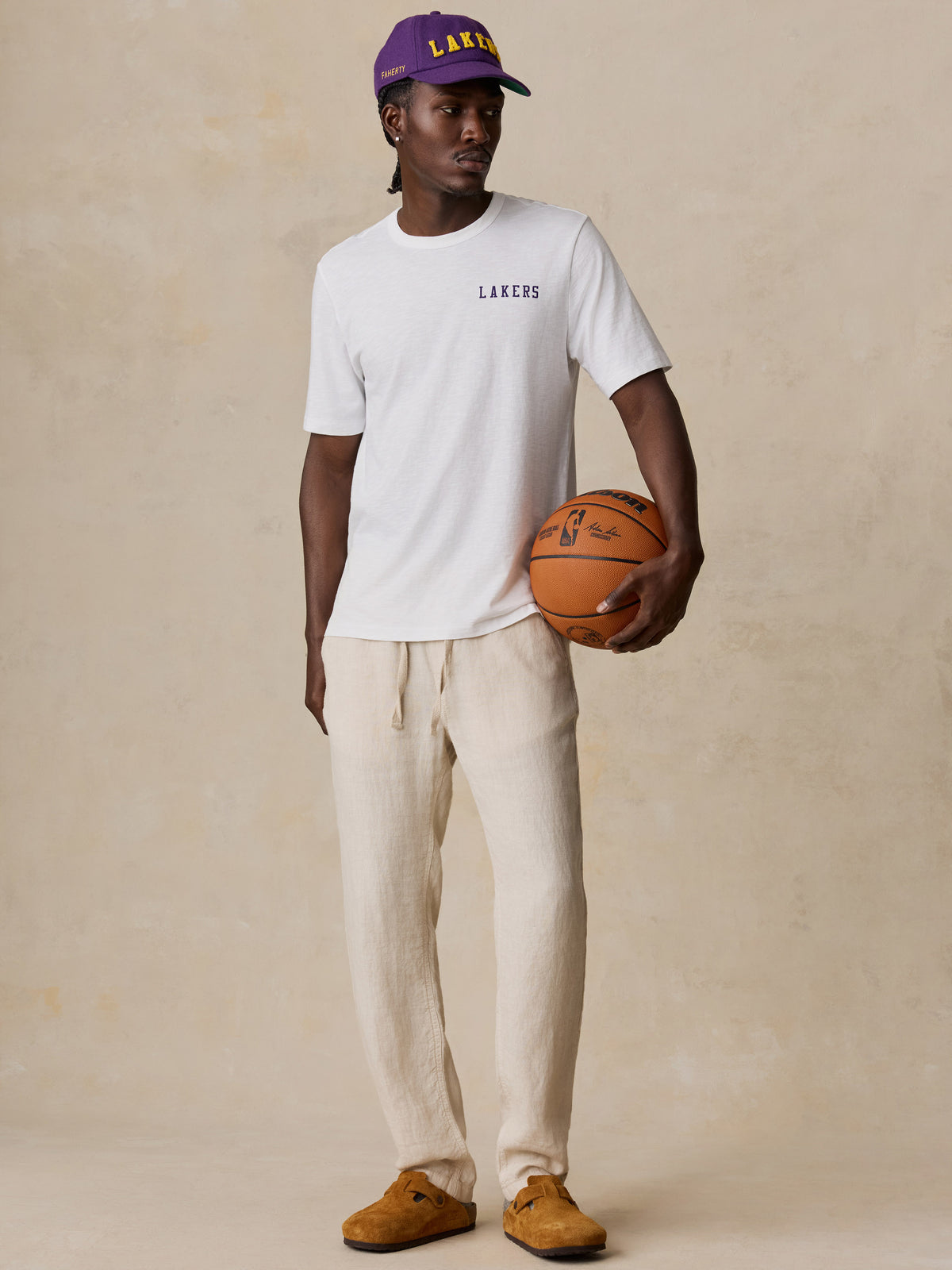 A man wearing a white LA Lakers tee and linen pants, image 1 of 6