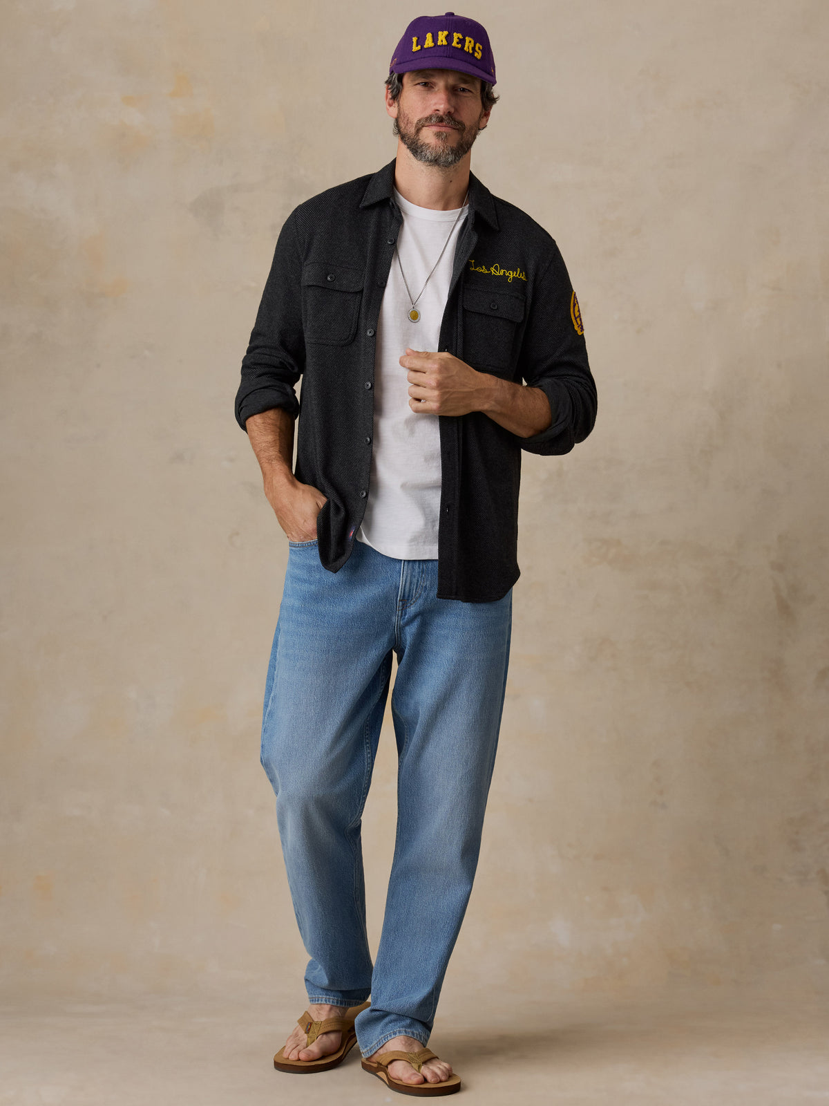 A man wearing a black LA Lakers shirt and blue jeans, image 4 of 6