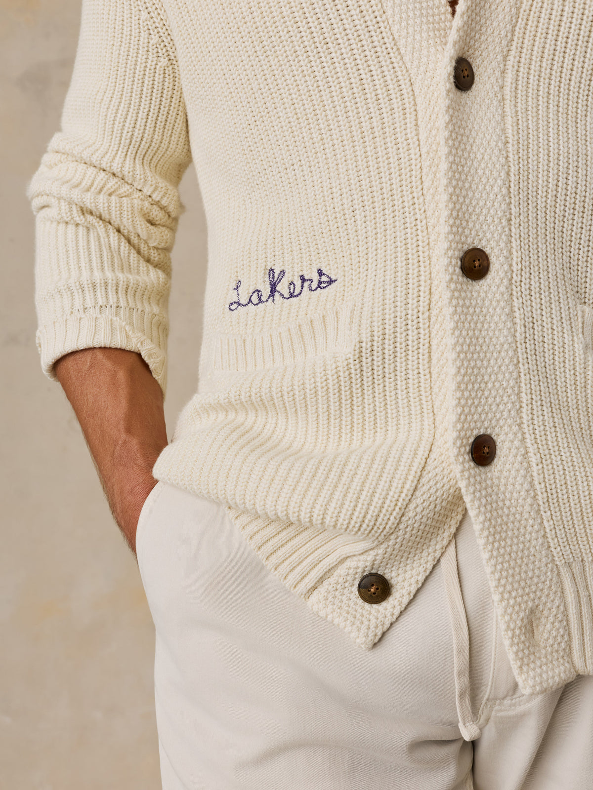Close up of a man wearing an off-white LA Lakers cardigan and white pants, image 4 of 7