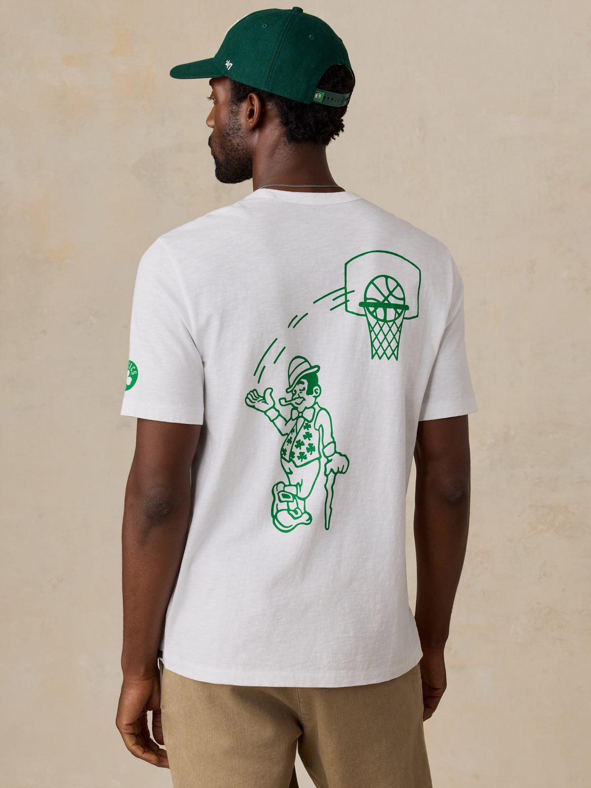 A man viewed from behind wearing a white Boston Celtics tee , image 2 of 6