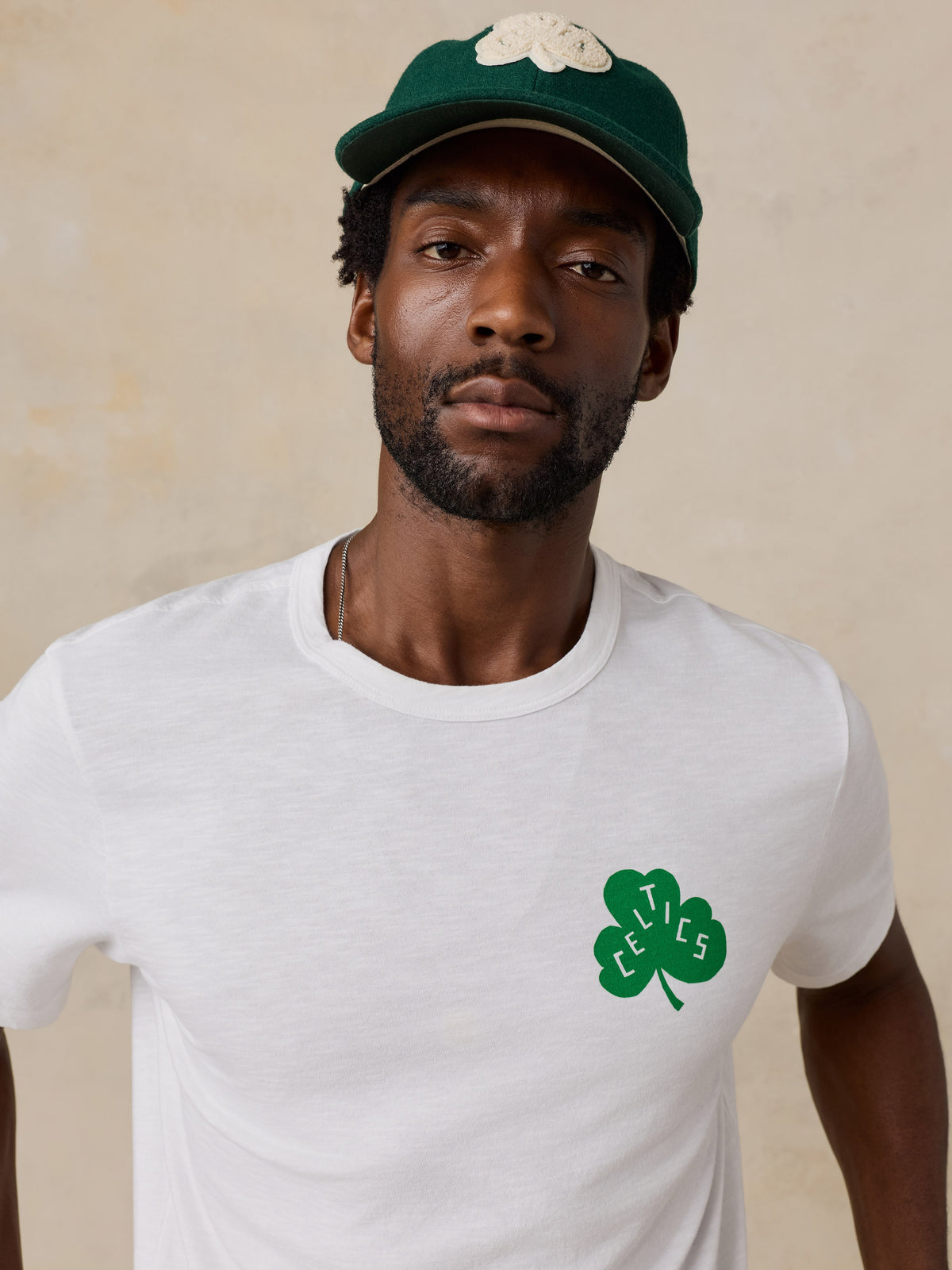 Close up of a man wearing a white Boston Celtics tee and hat, image 3 of 6