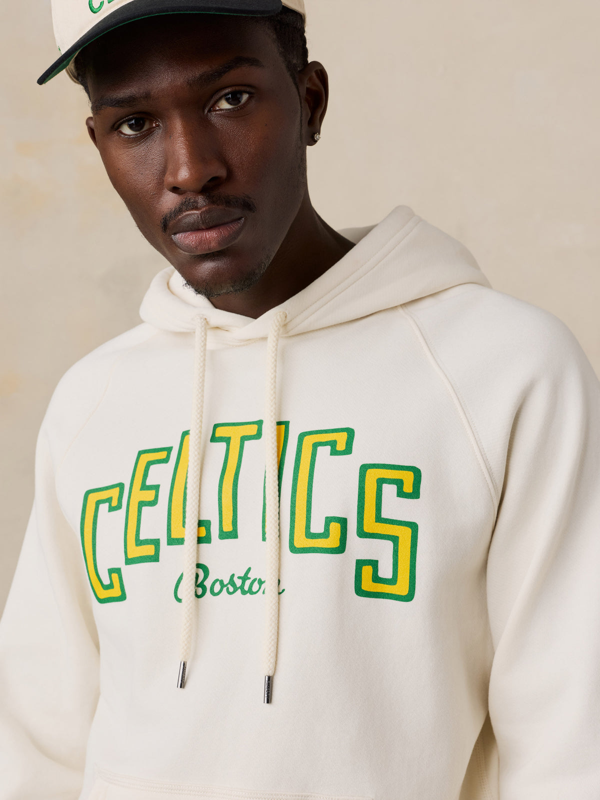 Close up of a man wearing a white Boston Celtics hoodie, image 3 of 6