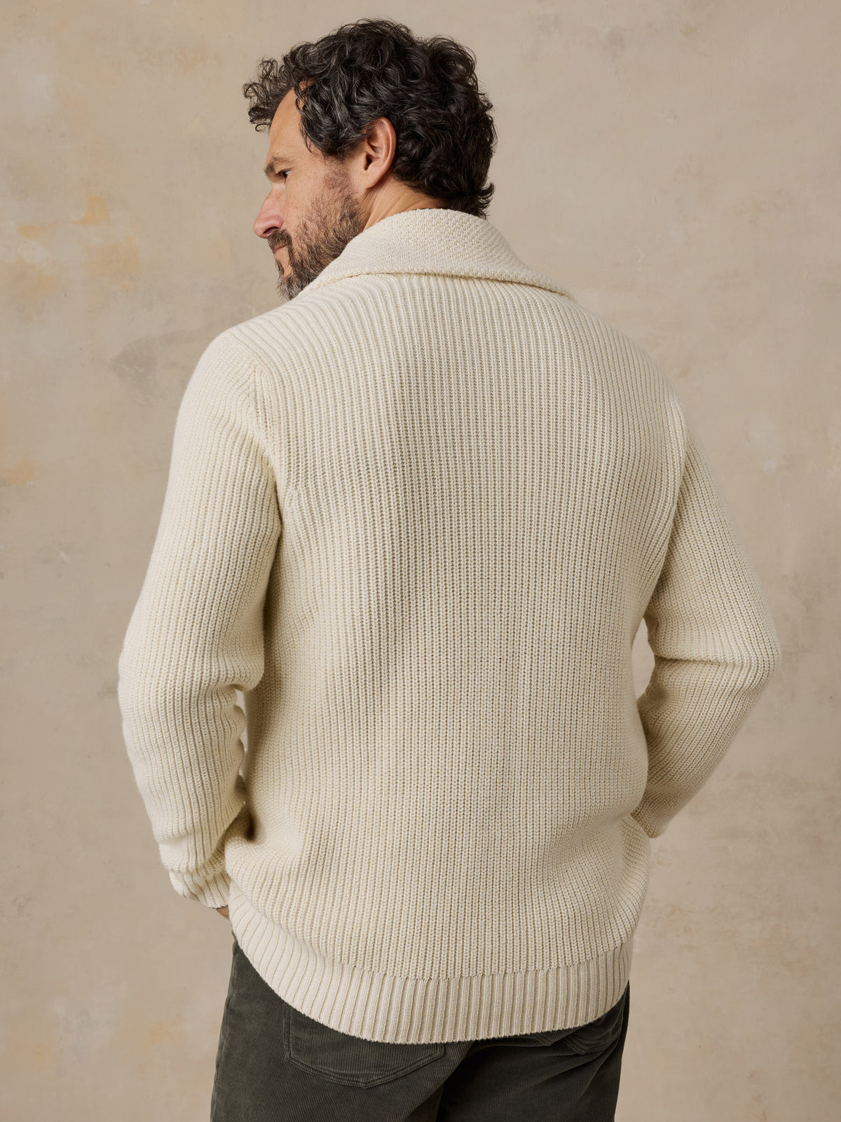 A man viewed from behind wearing an off-white Boston Celtics cardigan and green pants, image 5 of 7