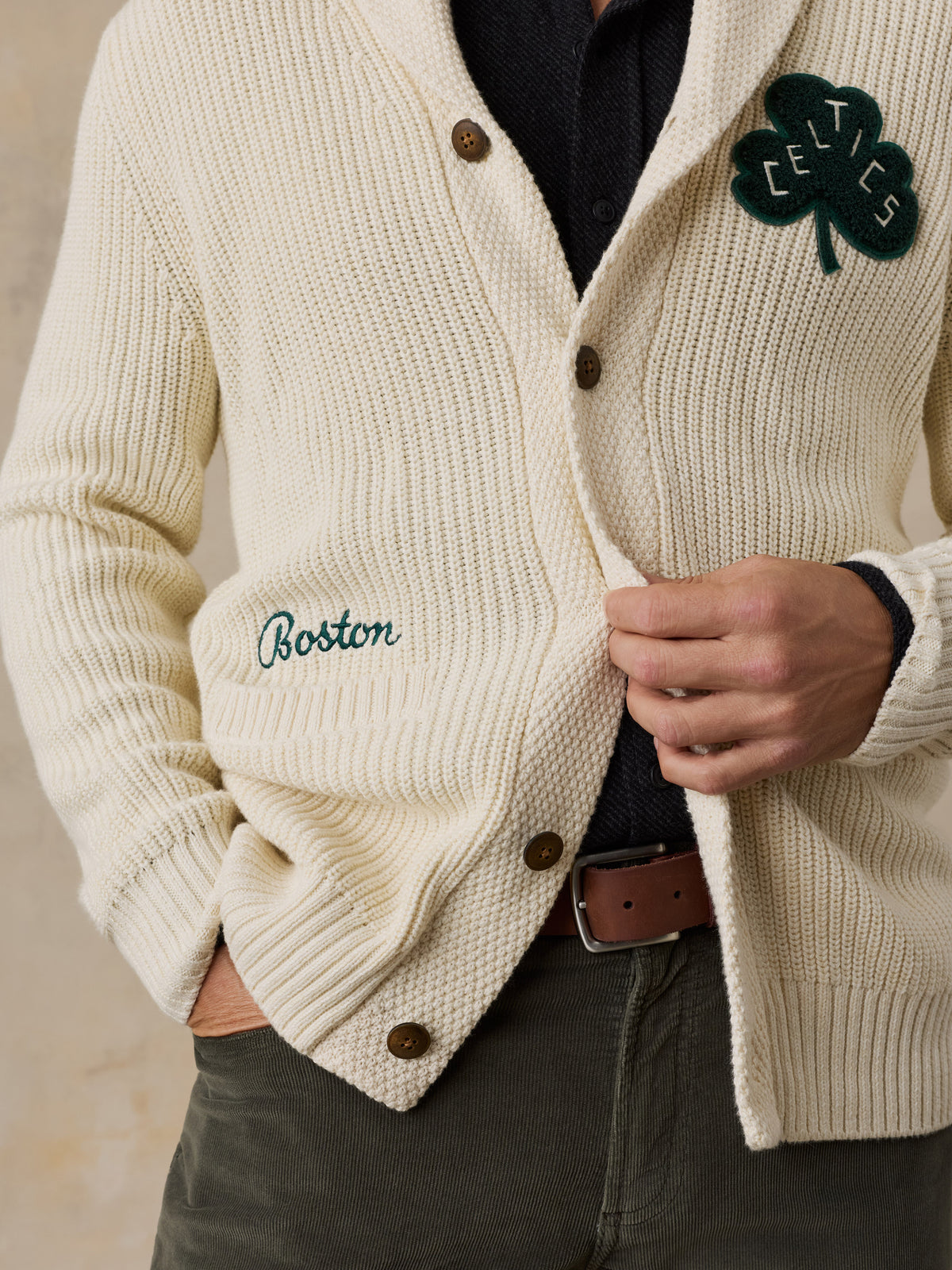 Close up of a man wearing an off-white Boston Celtics cardigan and green pants, image 2 of 7