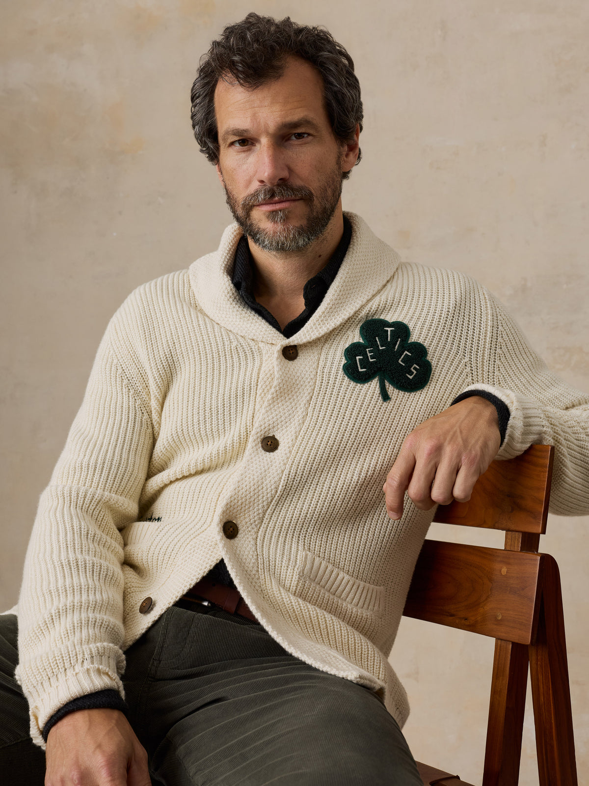 A man wearing an off-white Boston Celtics cardigan and green pants, image 4 of 7