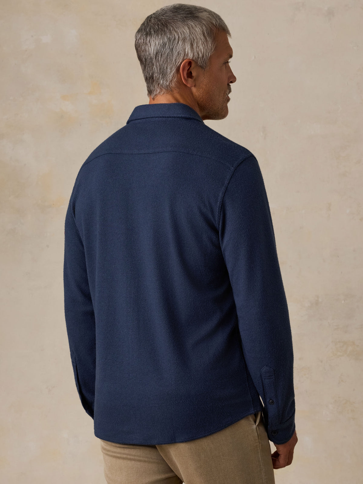 Man viewed from behind wearing a NY Giants button up shirt and beige pants, image 4 of 7