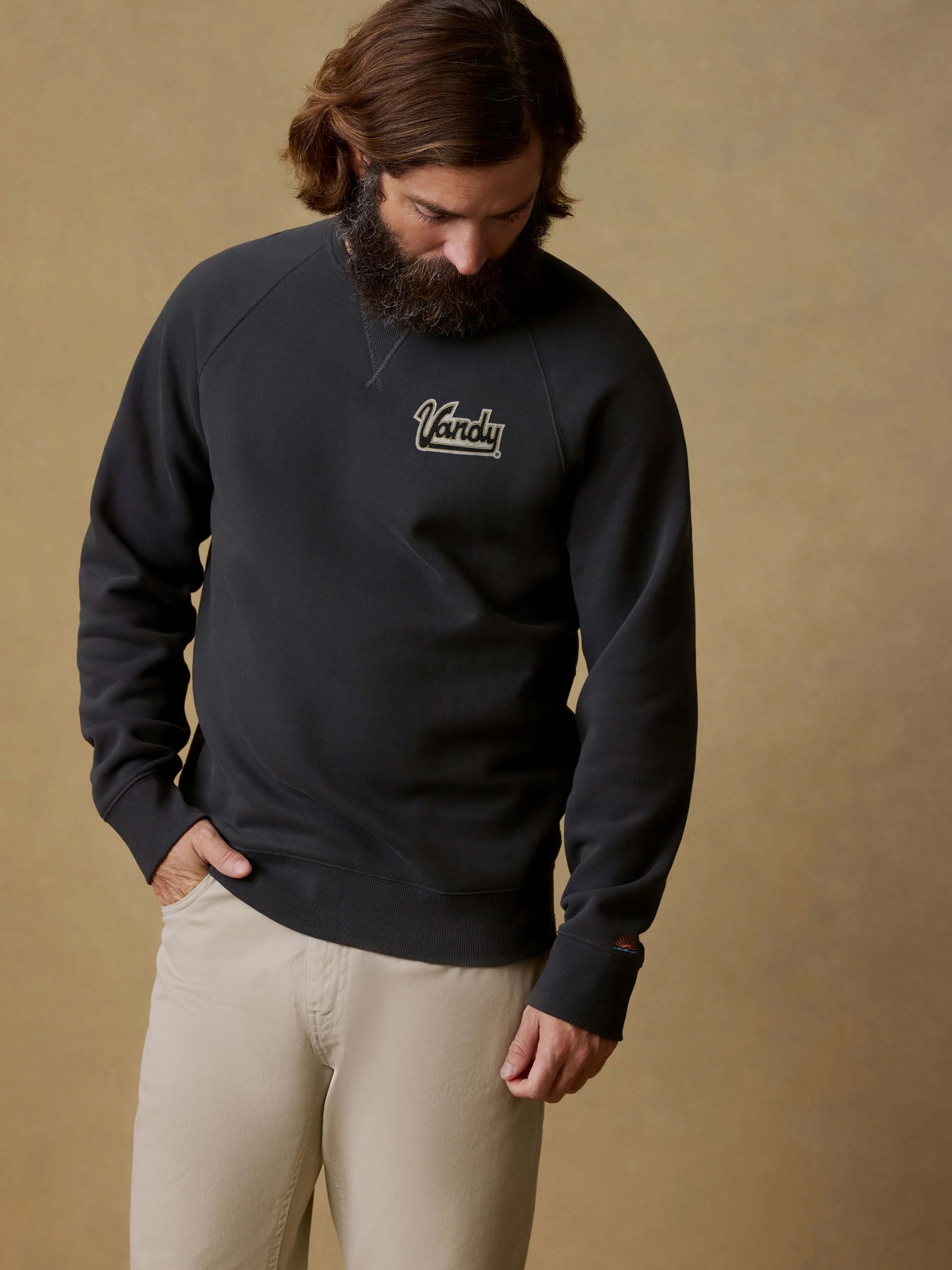 A man wearing a black Vanderbilt crewneck and beige pants