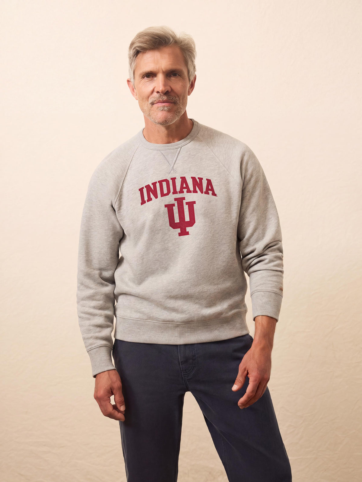 A man wearing a grey Indiana University crewneck and blue pants, image 1 of 1