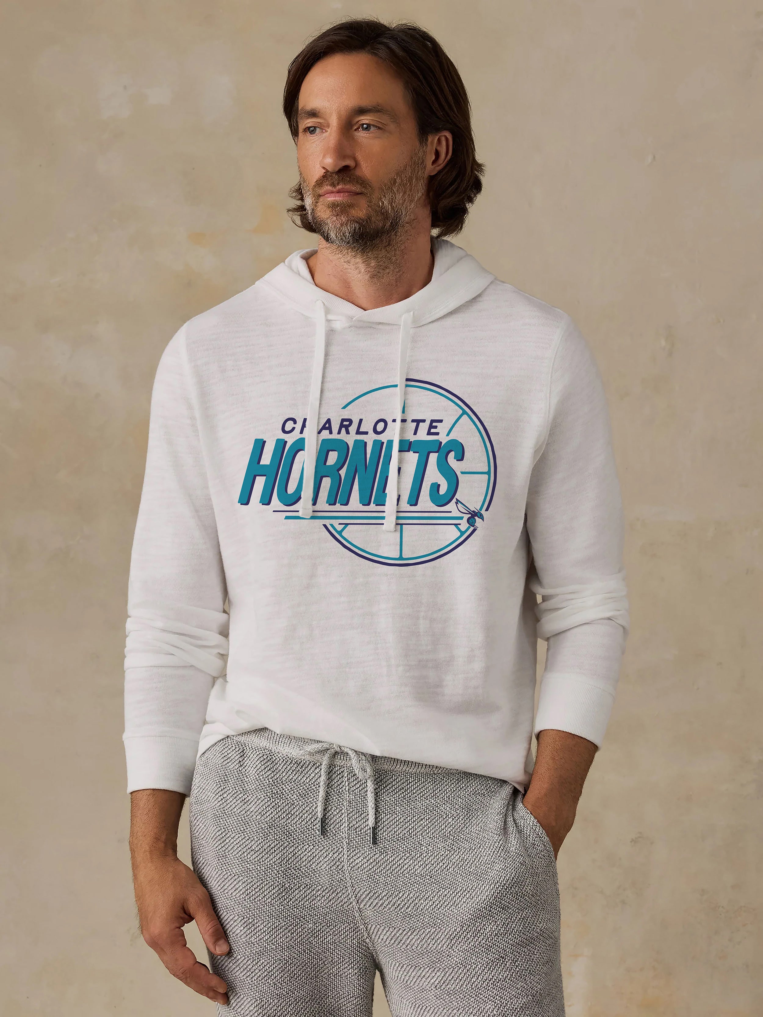 A man wearing a white Charlotte Hornets hoodie