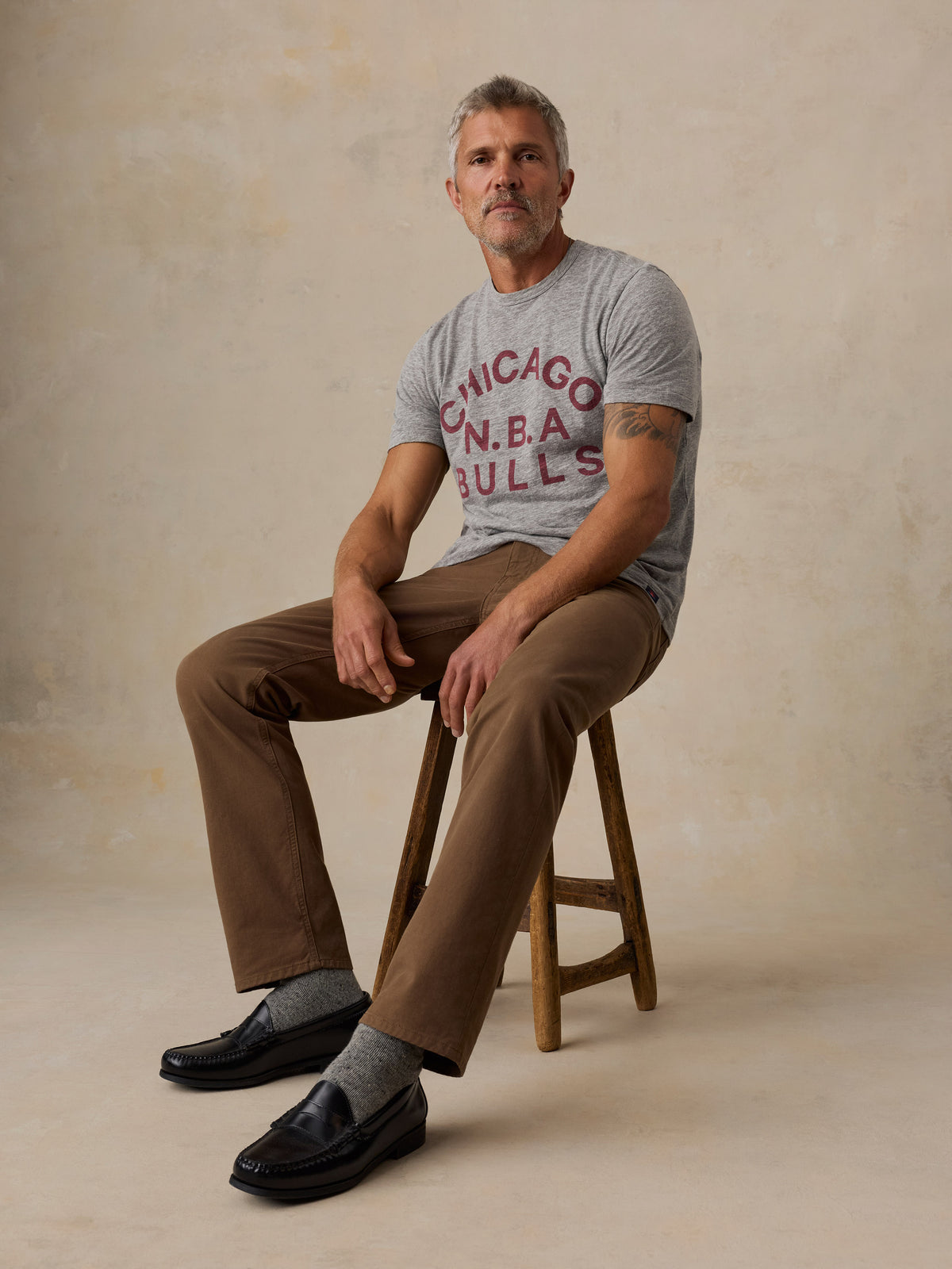 A man wearing a grey Chicago Bulls tee and brown pants, image 2 of 6