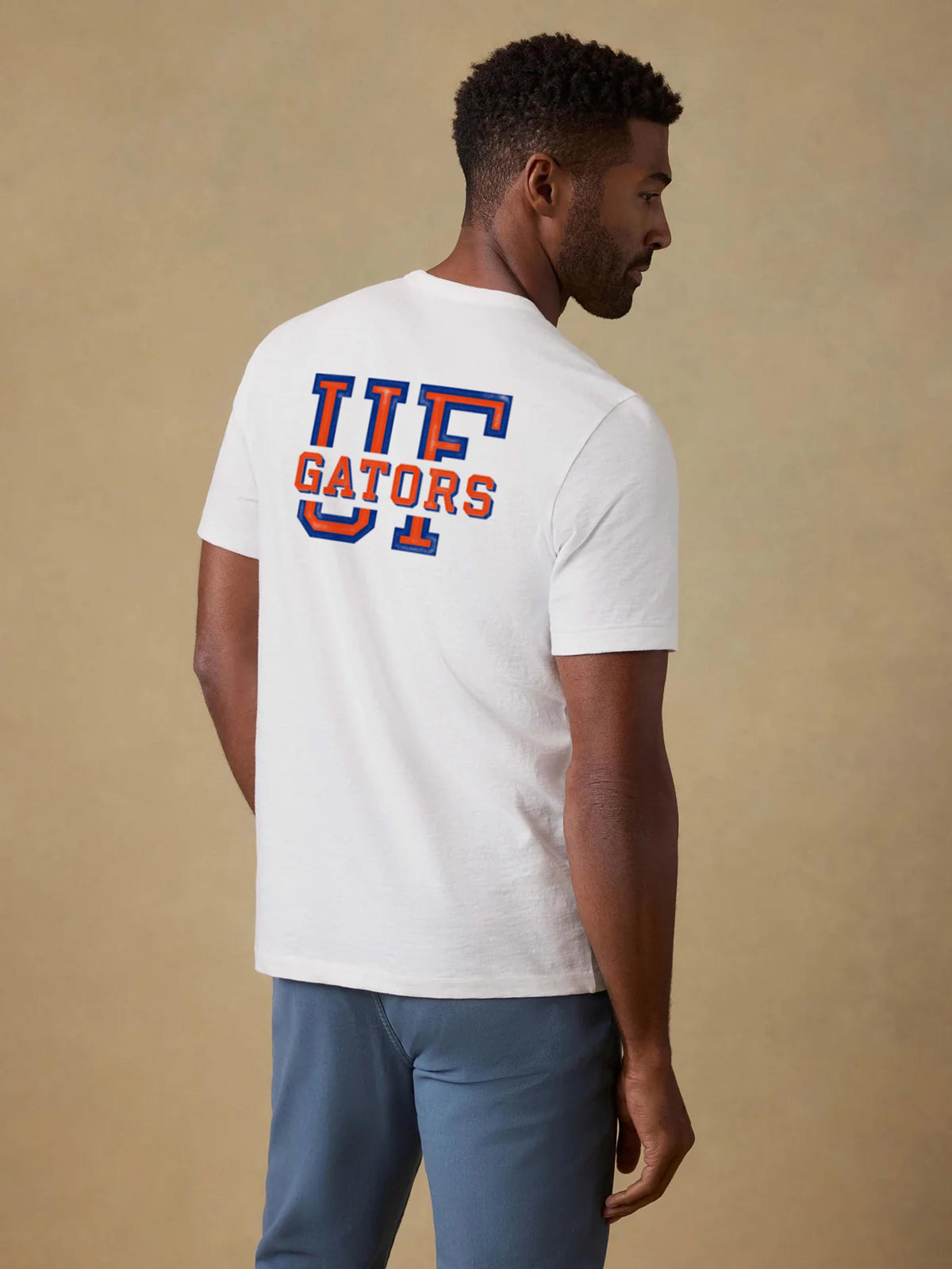 A man viewed from behind wearing a University of Florida tee and blue pants, image 2 of 2