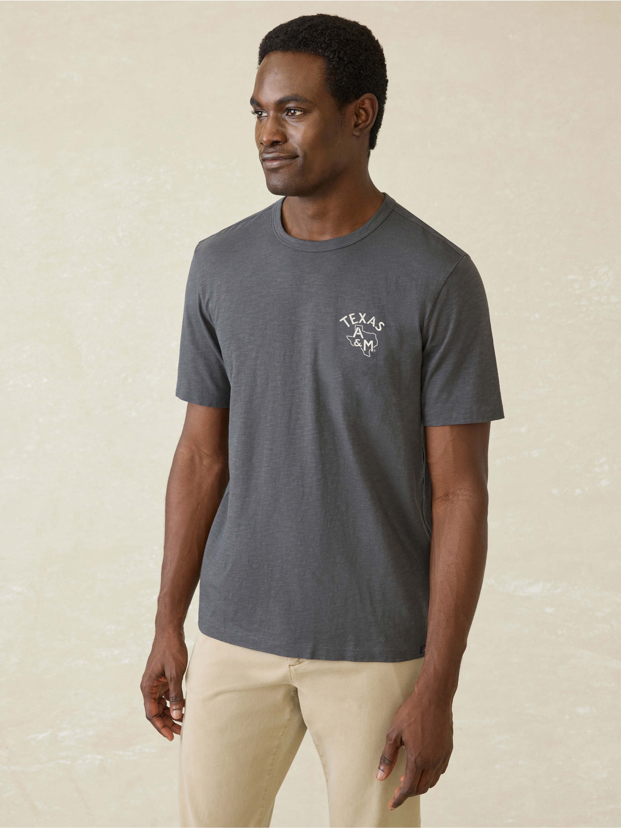 A man wearing a grey Texas A&M tee and beige pants