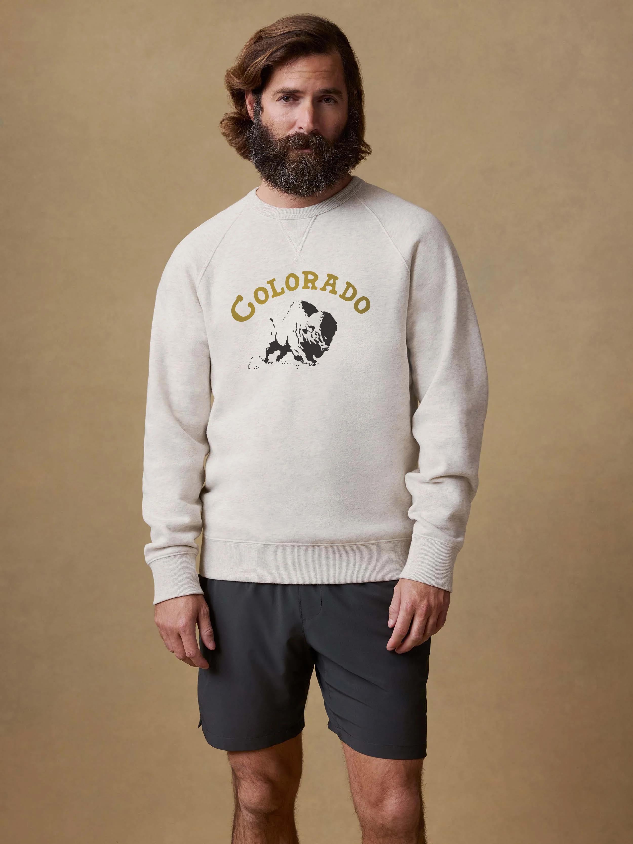 A man wearing a grey CU Boulder crewneck and black shorts