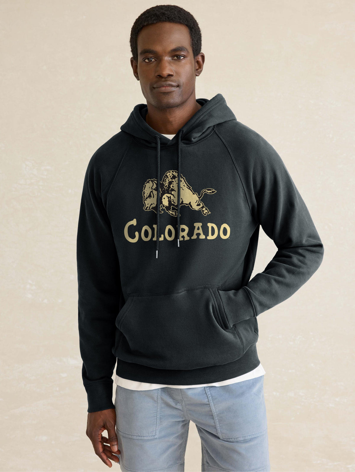 A man wearing a black CU Boulder hoodie and blue pants, image 1 of 1