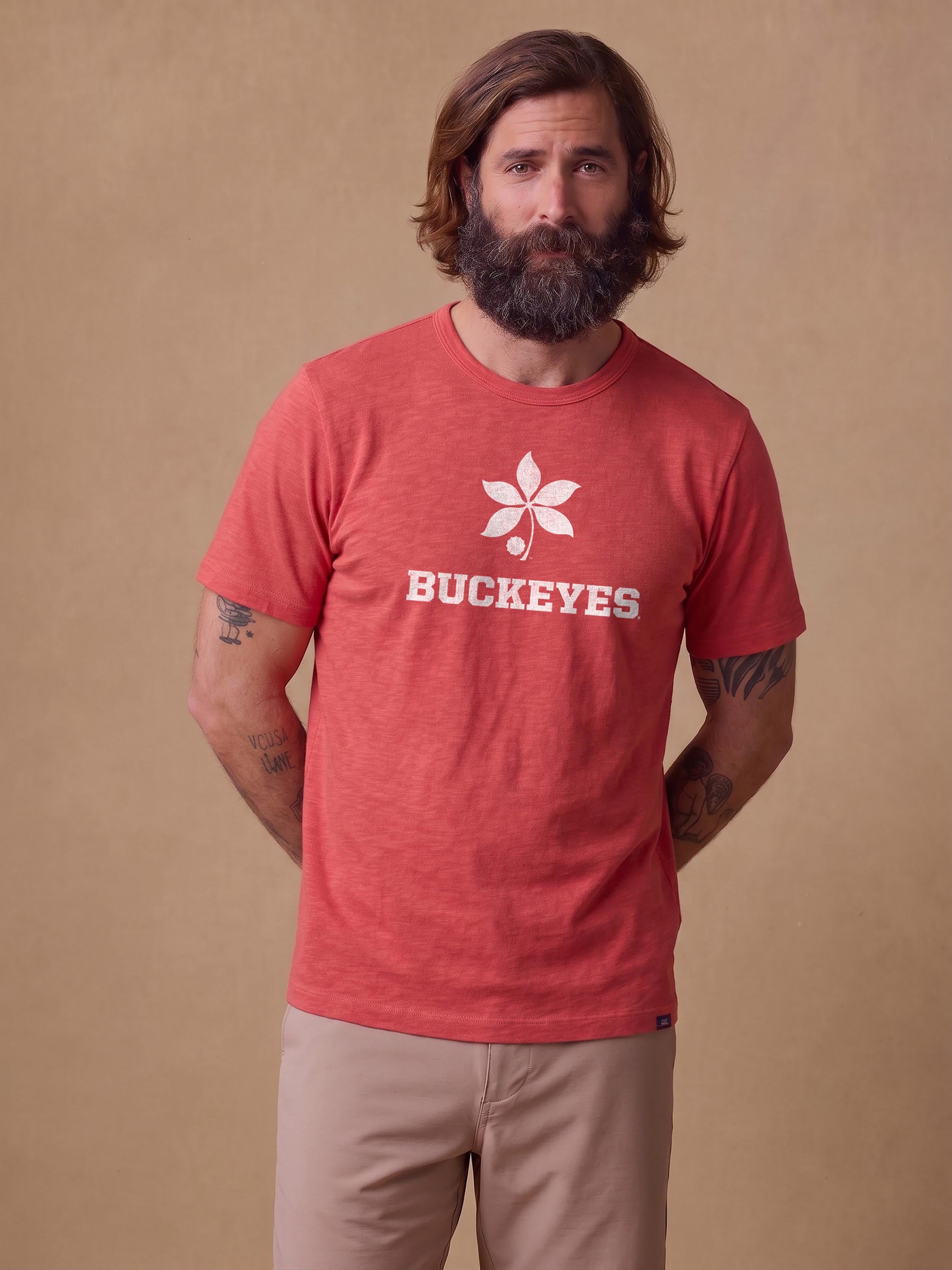 A man wearing a red Ohio State tee and beige shorts
