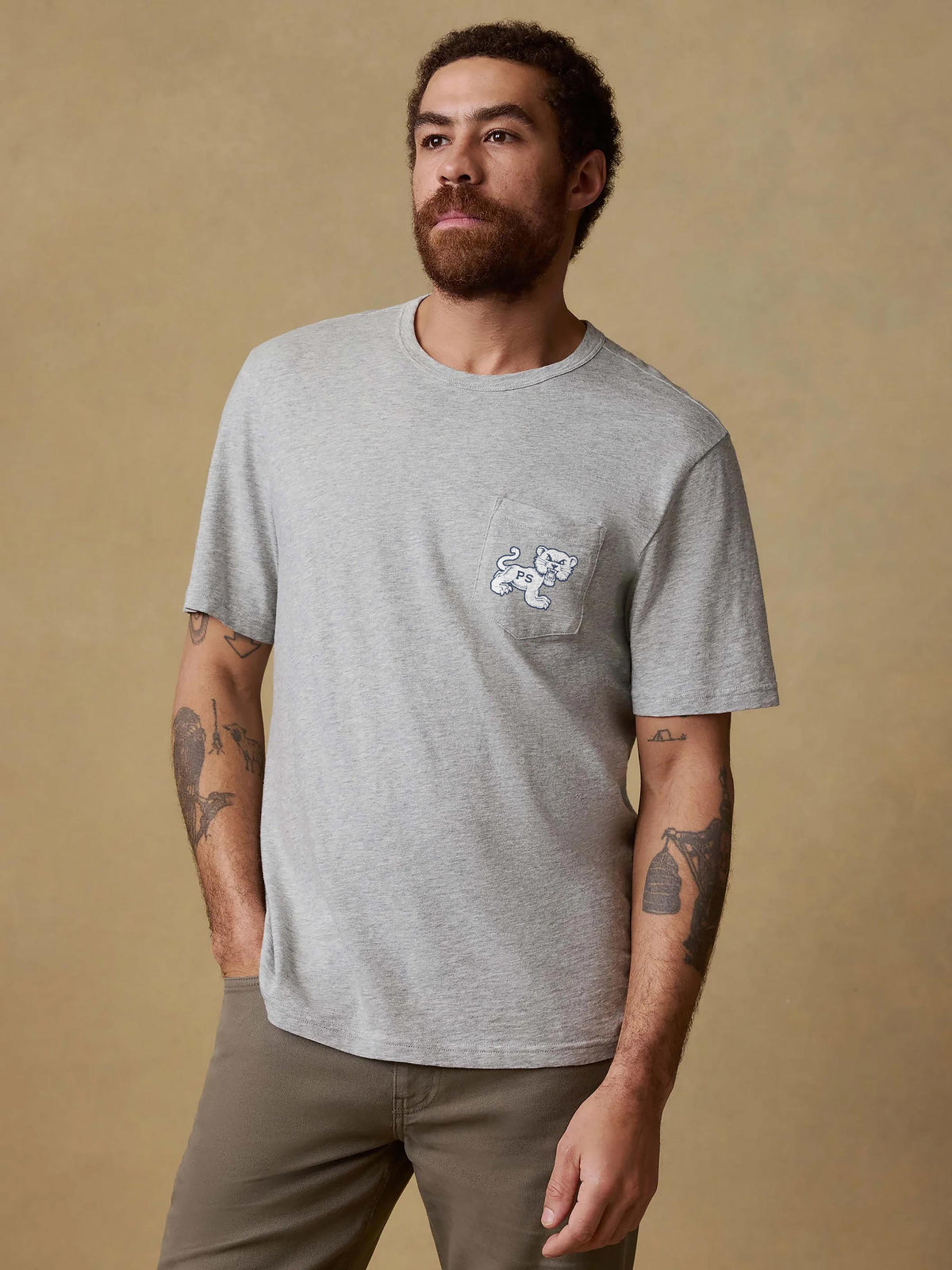 A man wearing a grey Penn State tee and brown pants, image 1 of 2