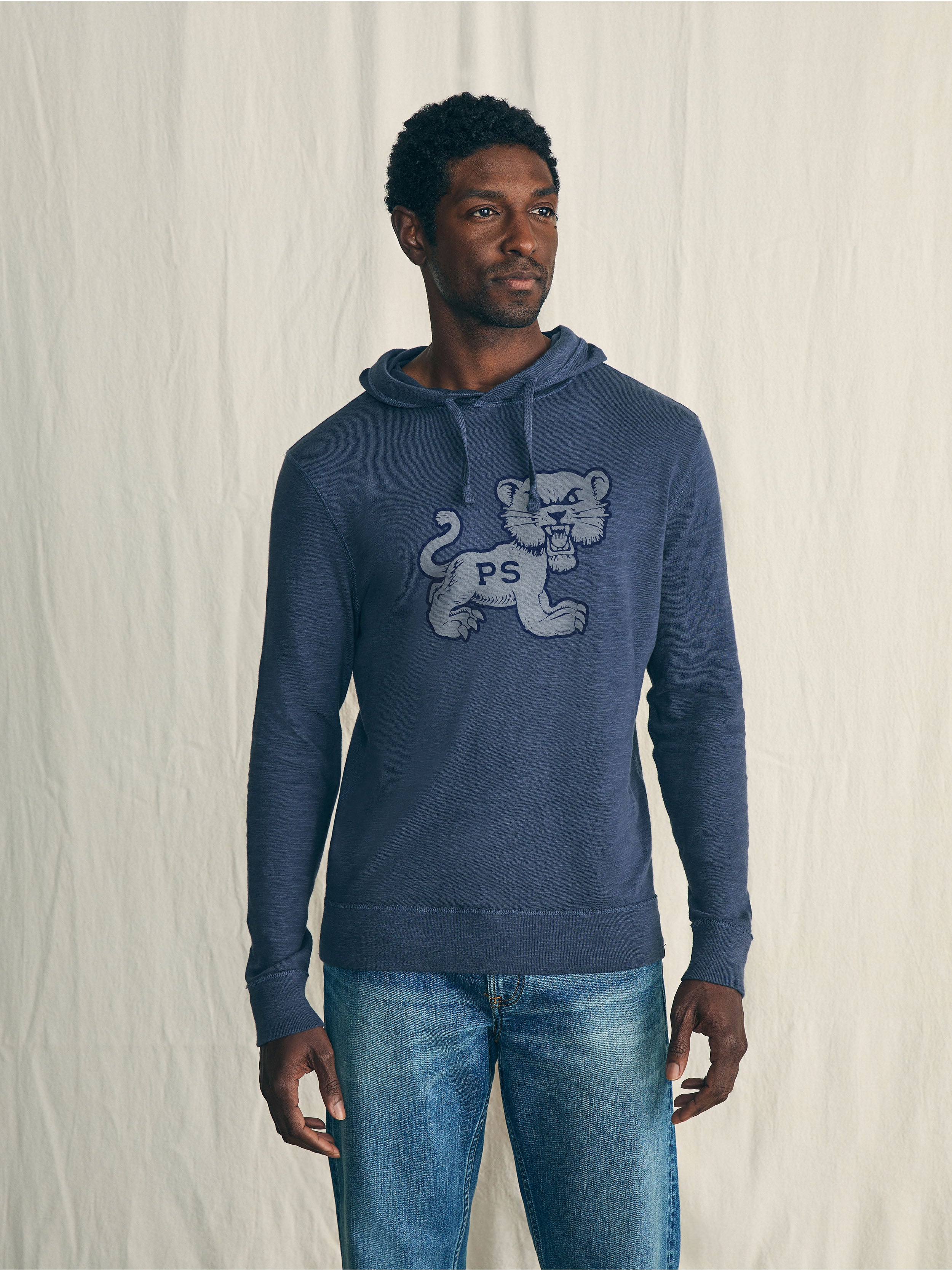 A man wearing a blue Penn State hoodie and blue jeans