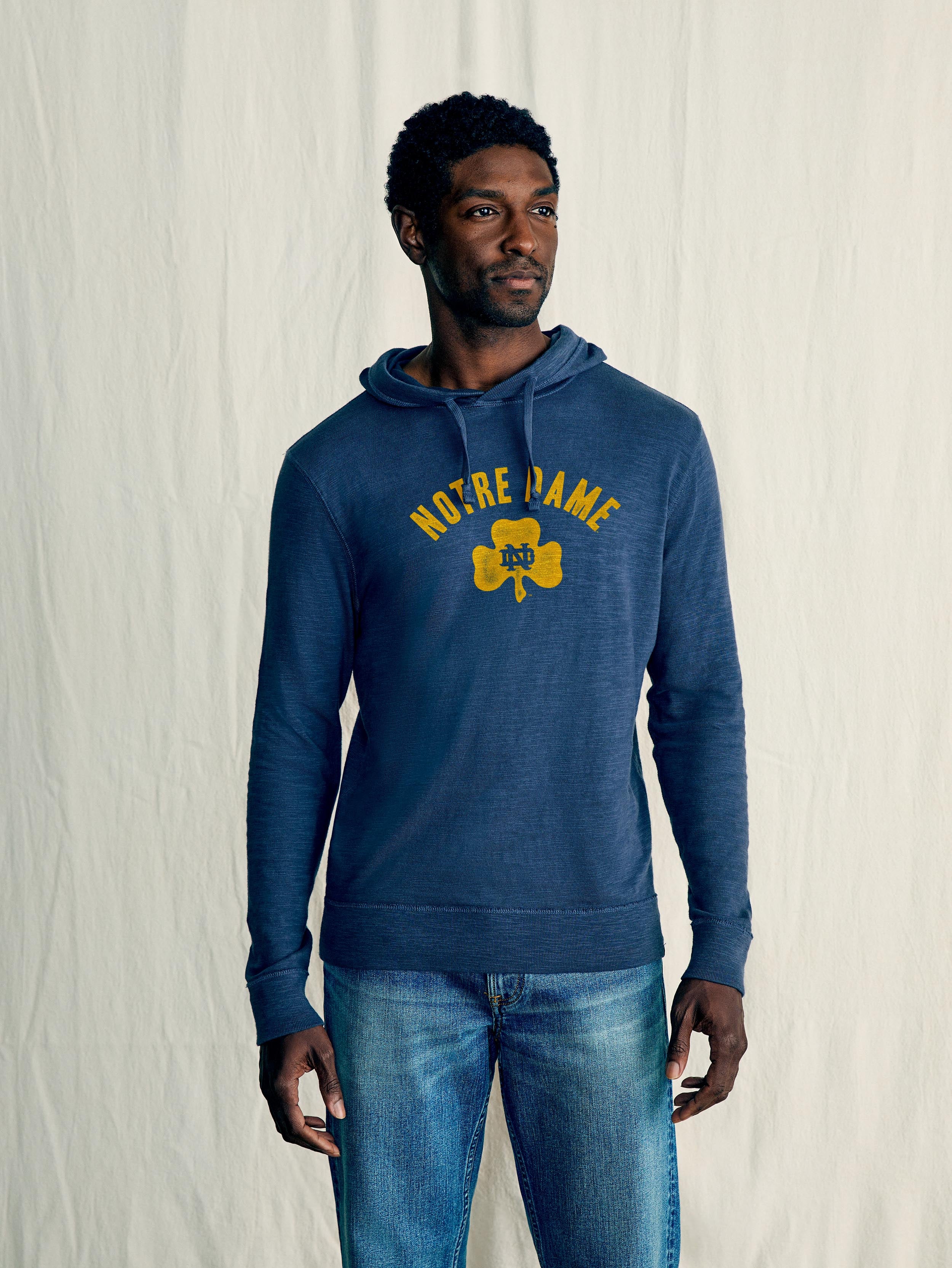 A man wearing a blue Notre Dame hoodie and blue jeans