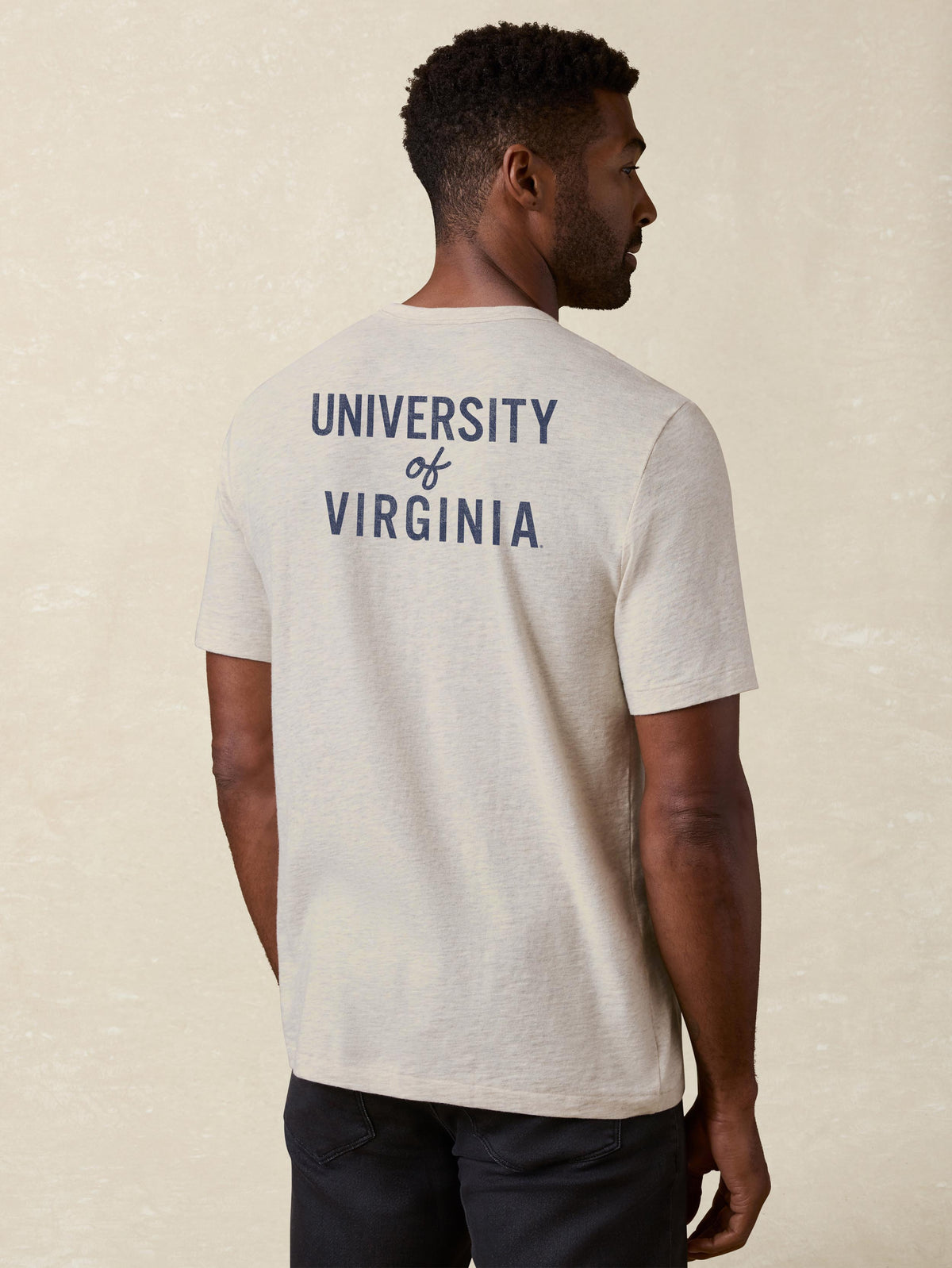 A man viewed from behind wearing a grey University of Virginia tee and black pants, image 2 of 2