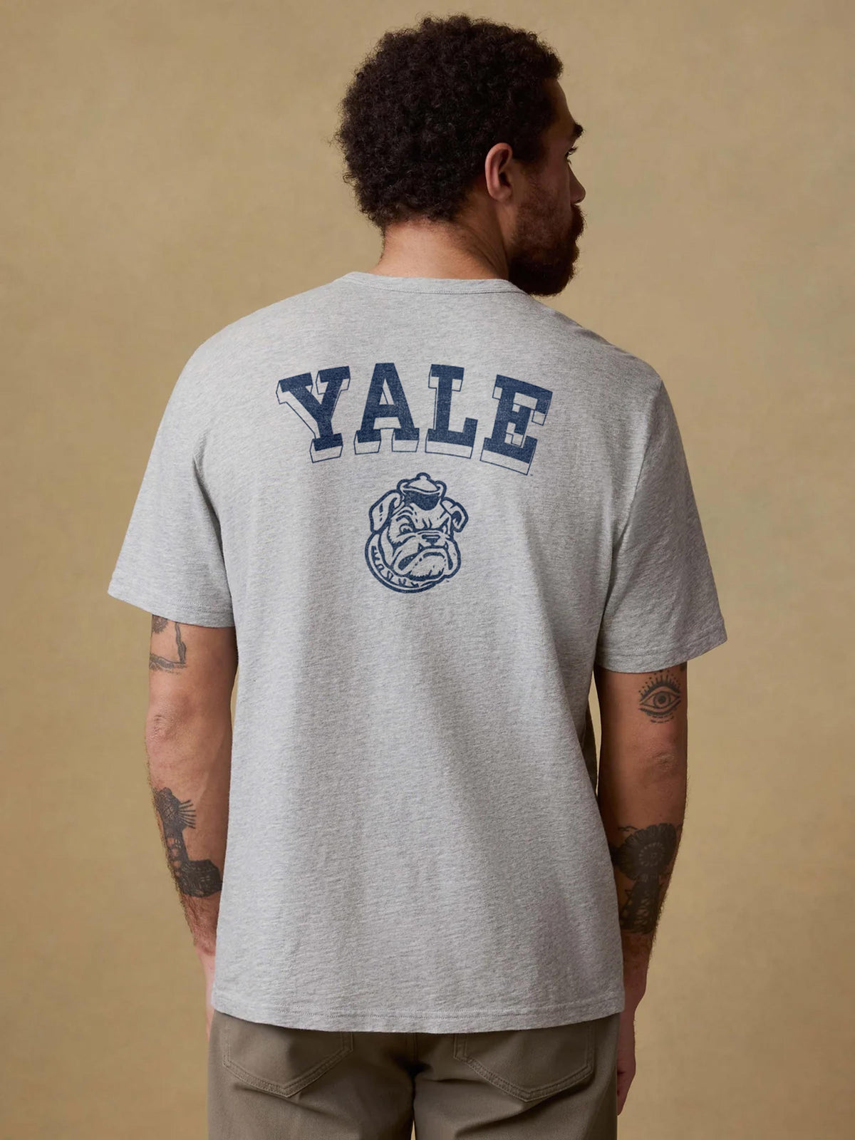 A man viewed from behind wearing a grey Yale tee and brown pants, image 2 of 2