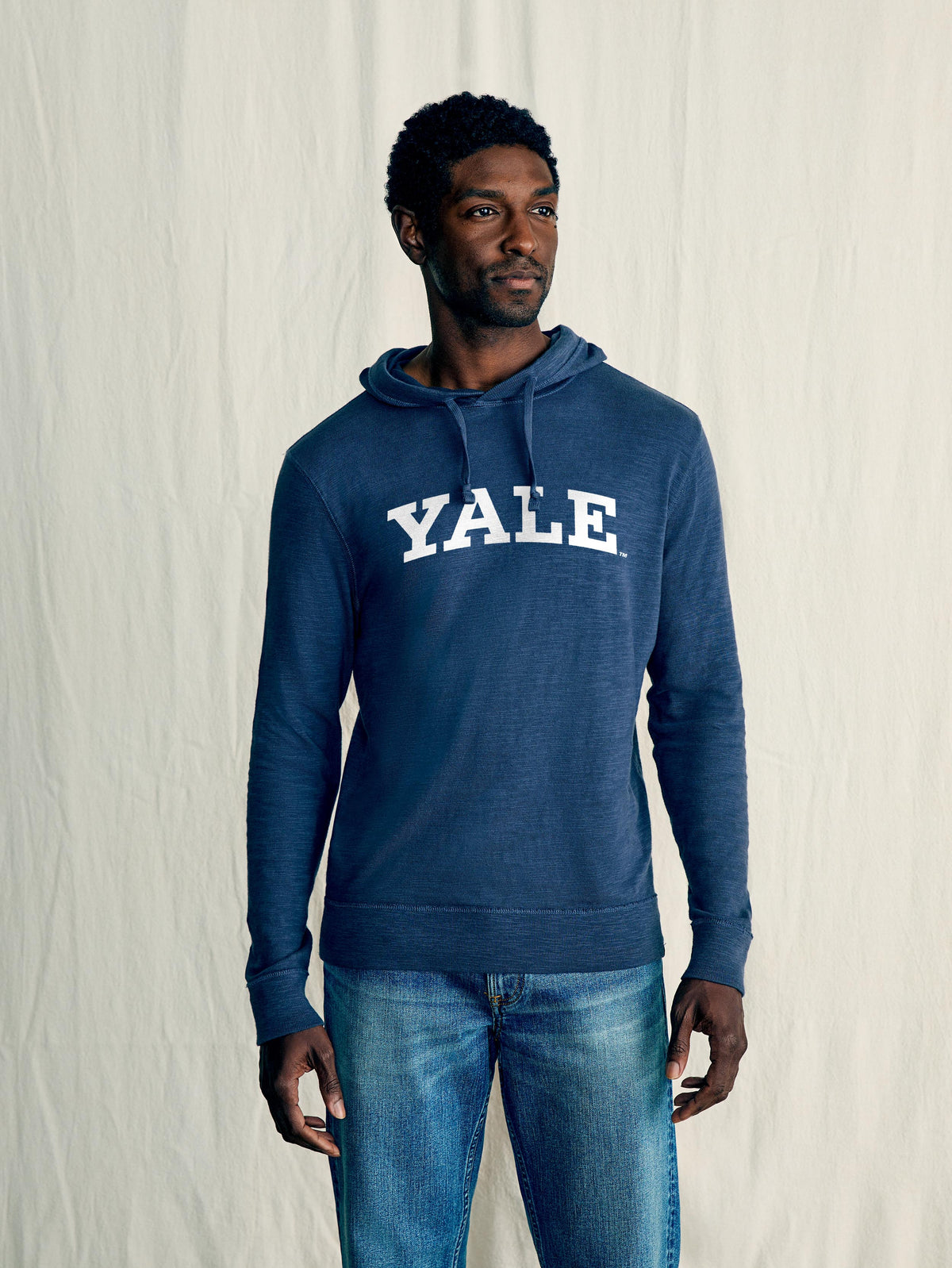A man wearing a blue Yale hoodie and blue jeans, image 1 of 1