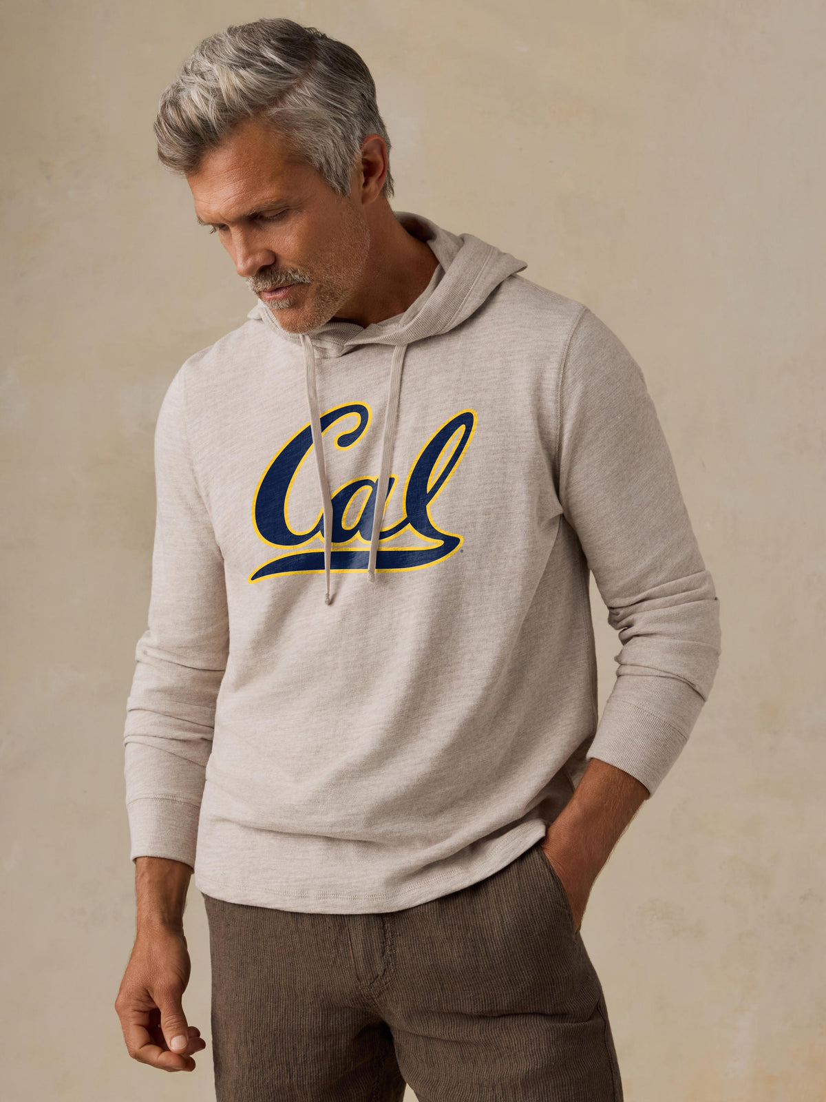 A man wearing a grey UC Berkeley hoodie and brown shorts, image 1 of 1