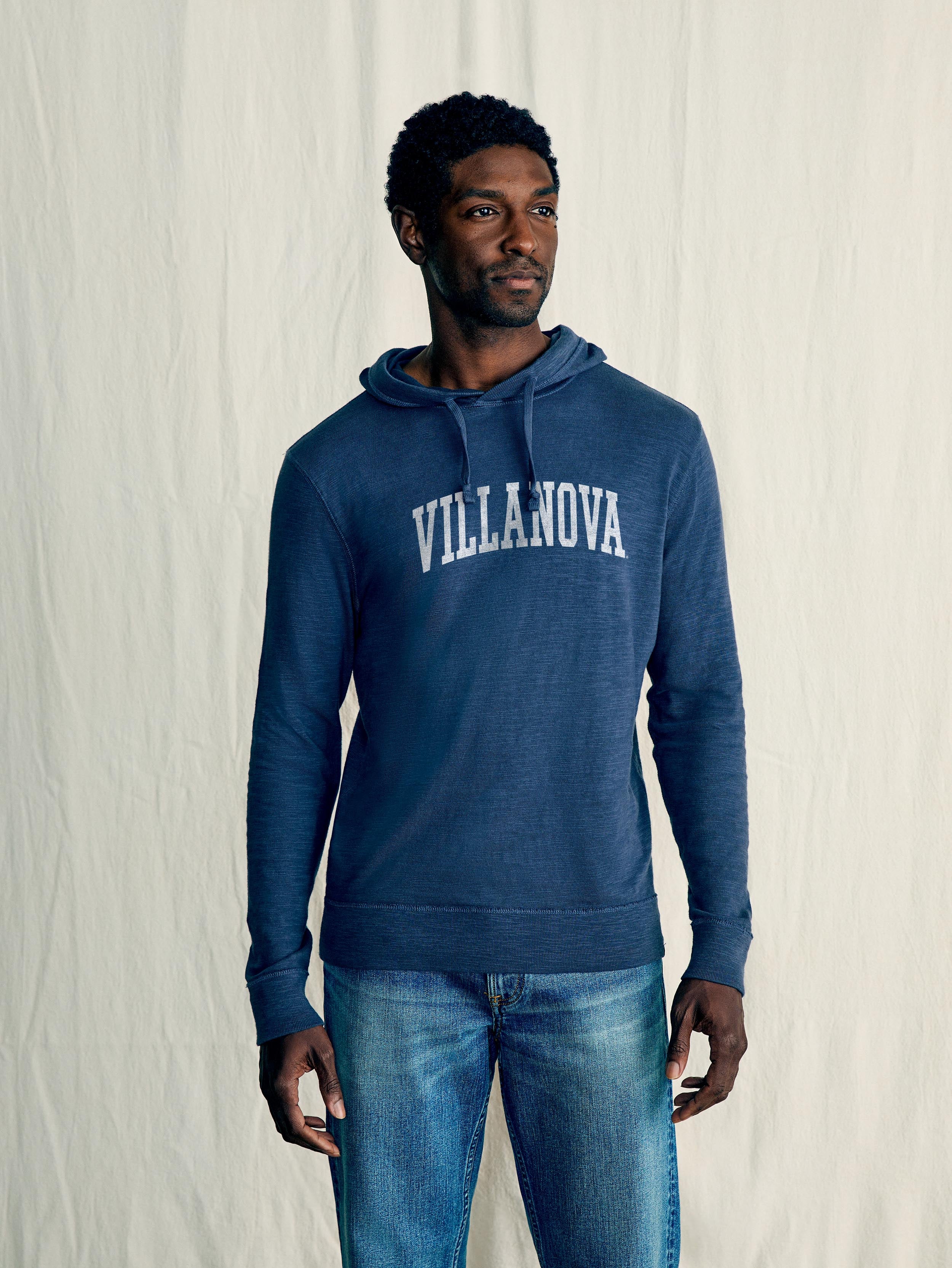 A man wearing a blue Villanova hoodie and blue jeans