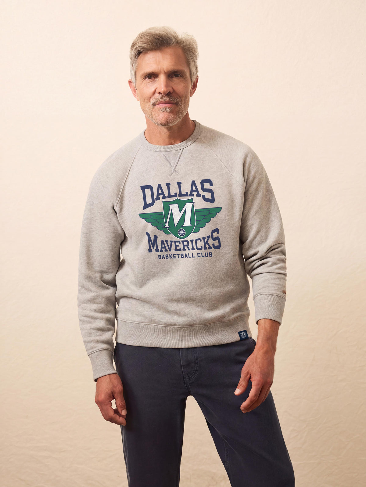 A man wearing a grey Dallas Mavericks crewneck, image 1 of 2