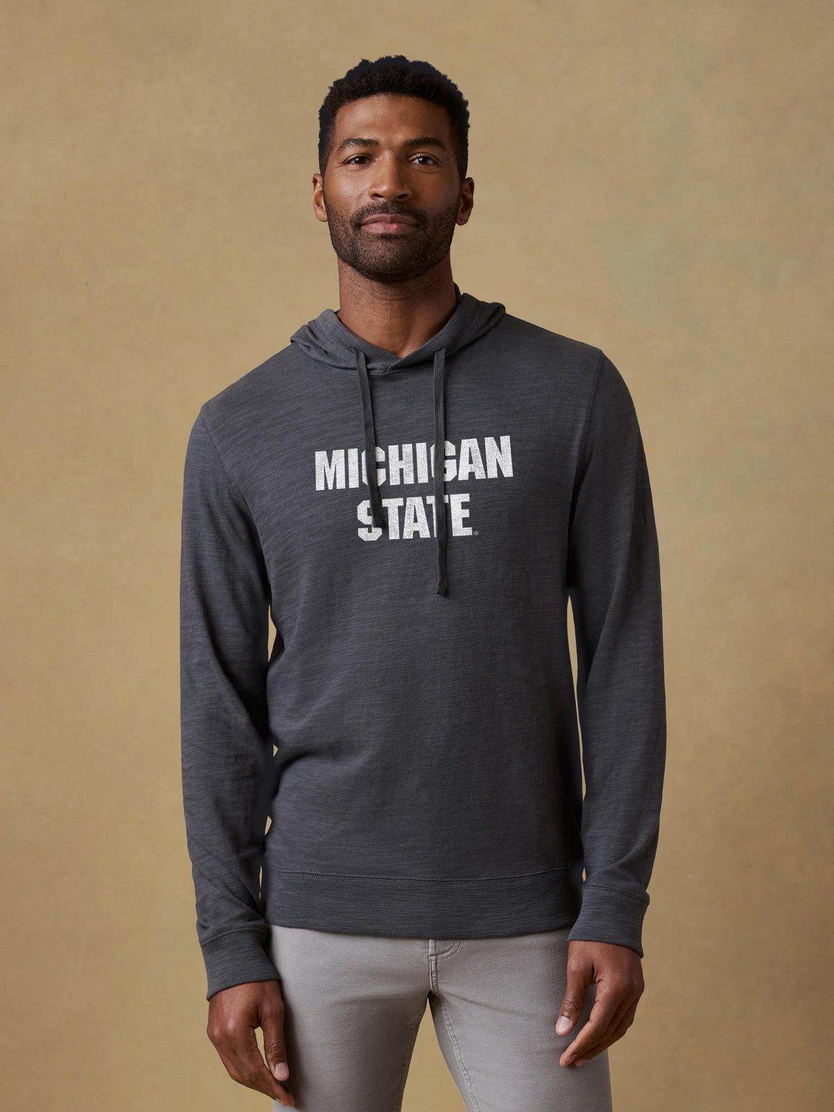 A man wearing a grey Michigan State hoodie and light grey pants, image 1 of 1