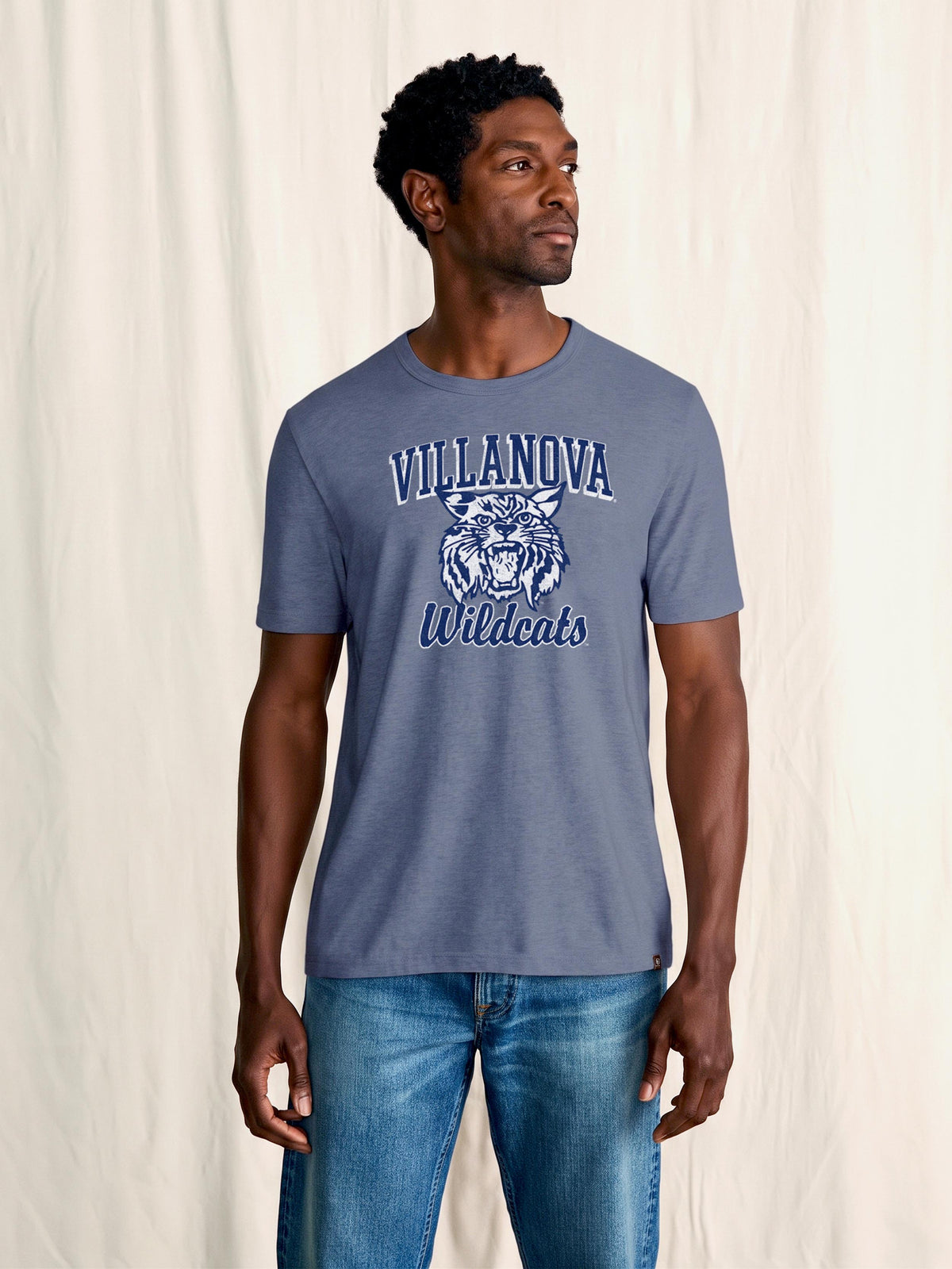 A man wearing a blue Villanova tee and blue jeans, image 1 of 1