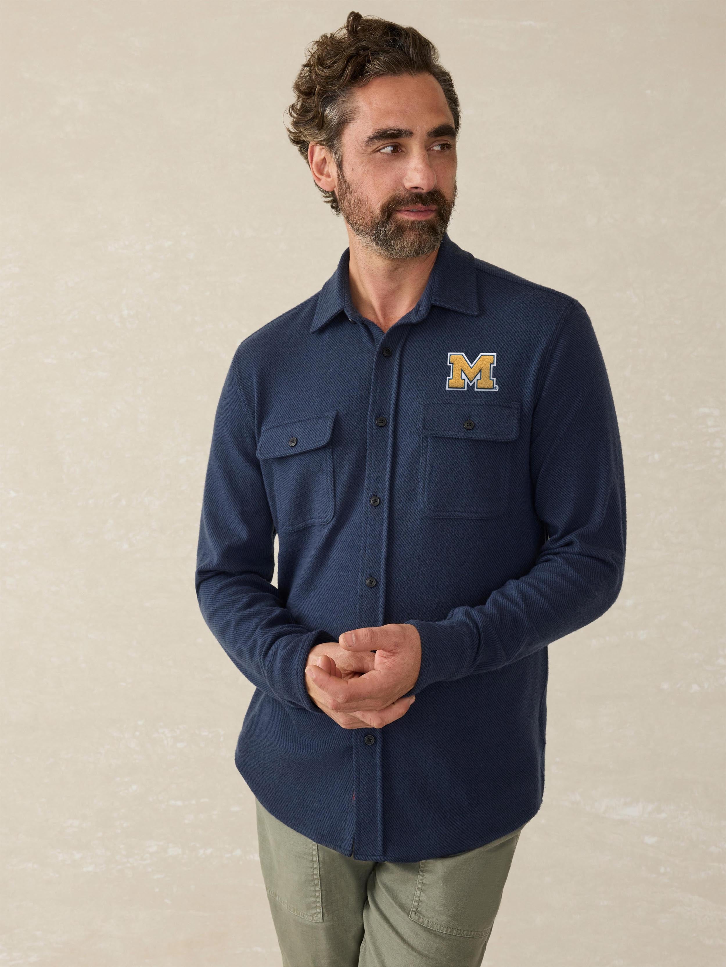 A man wearing a blue University of Michigan shirt and green pants
