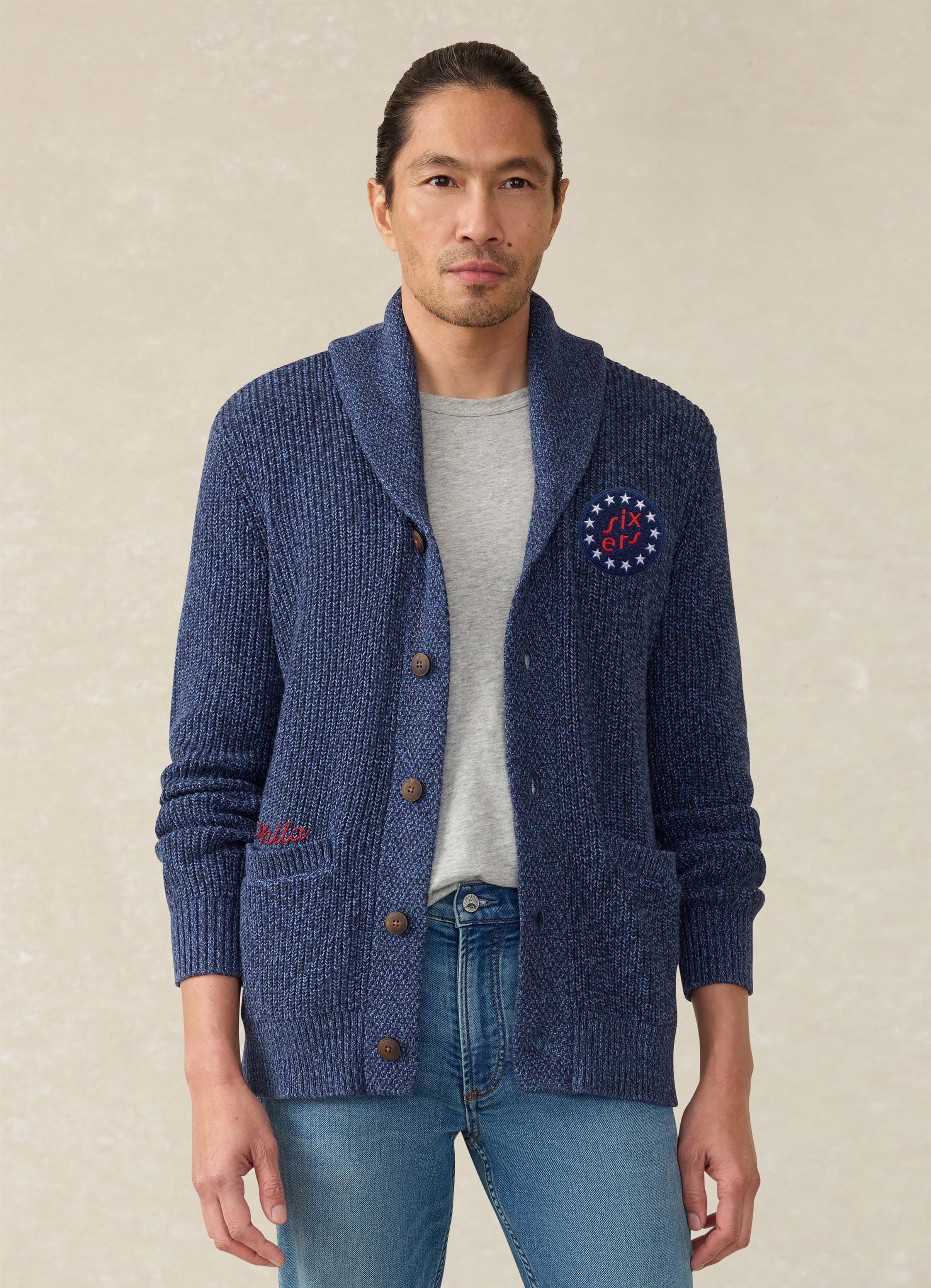 A man wearing a blue Philadelphia 76ers cardigan