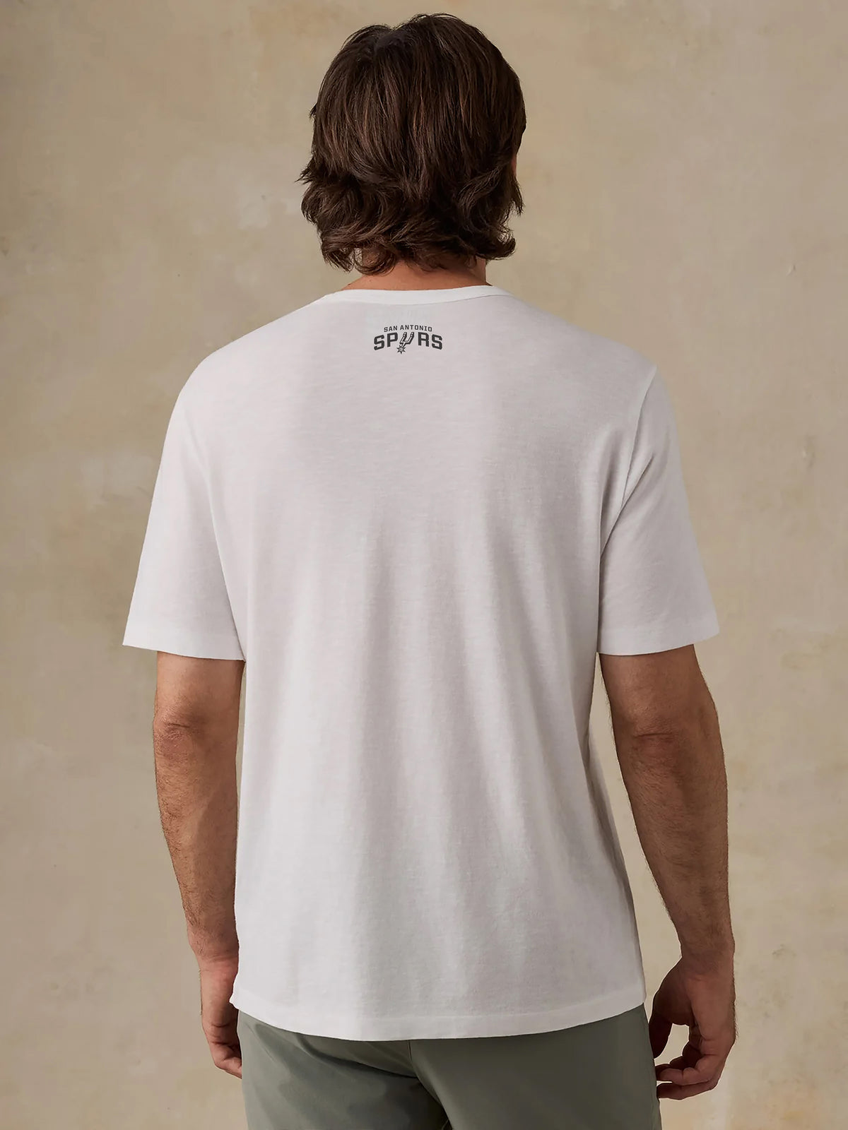 A man viewed from behind wearing a white San Antonio Spurs tee, image 2 of 4