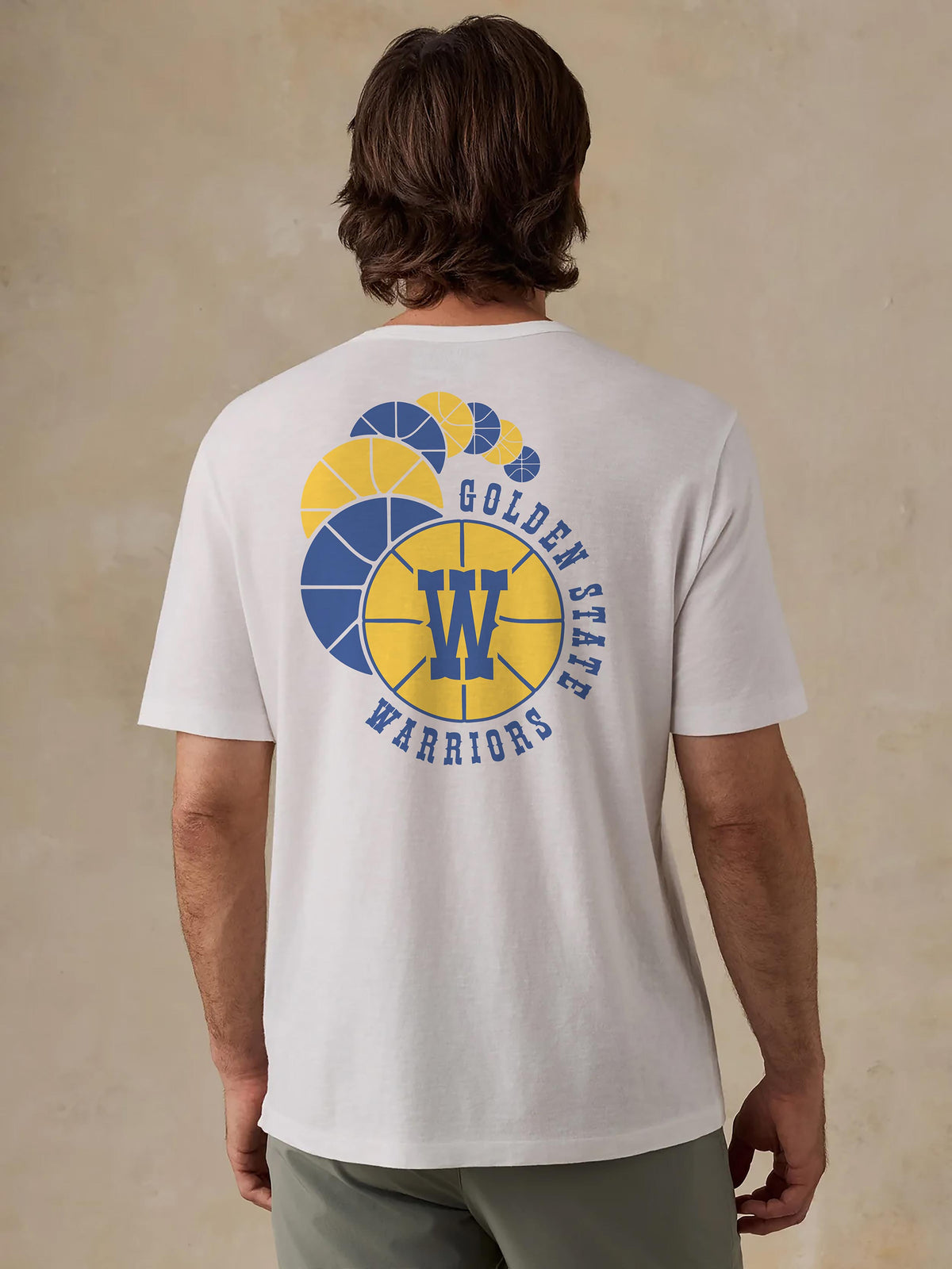 A man viewed from behind wearing a white Golden State Warriors tee, image 2 of 4