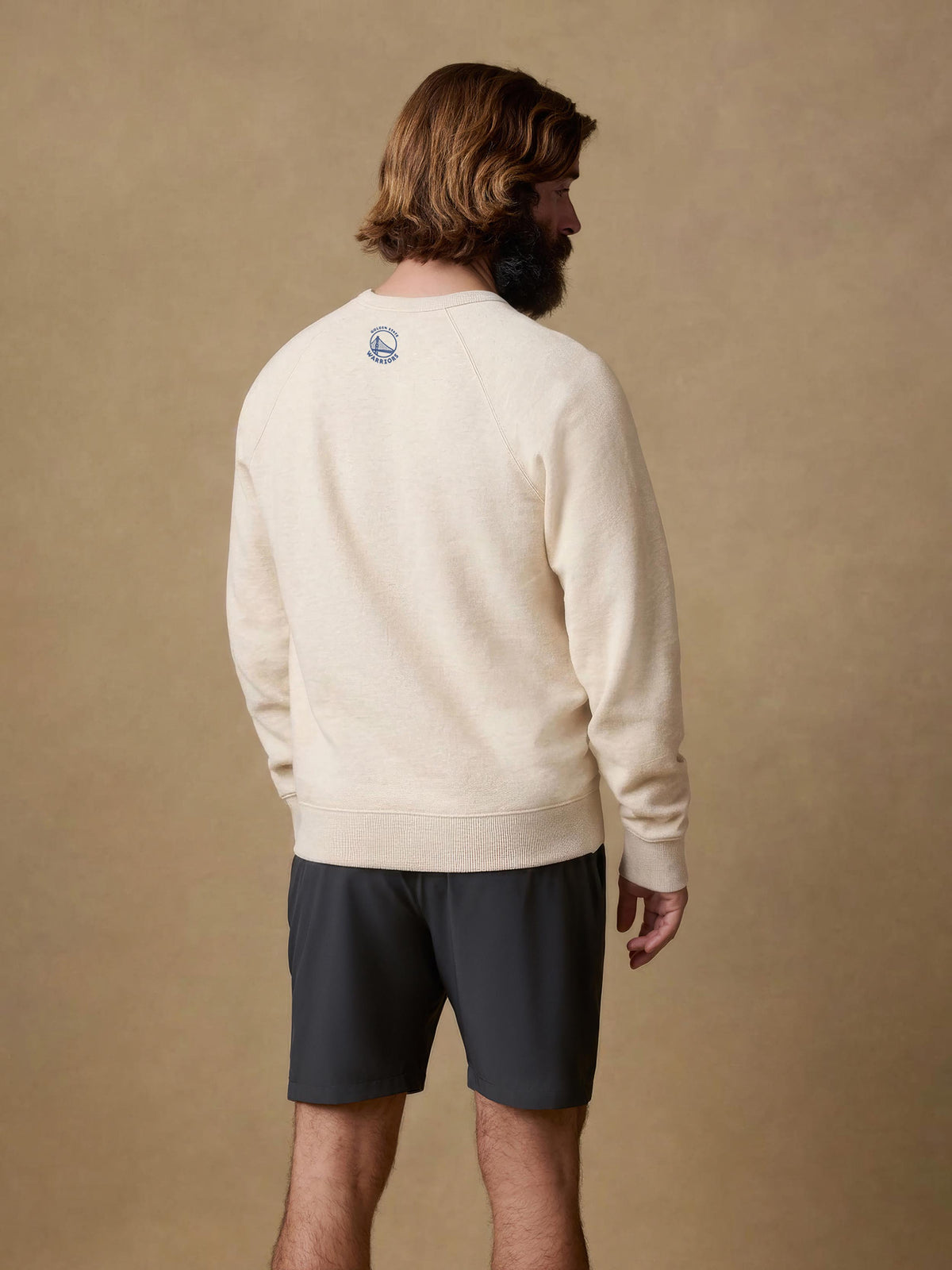 A man viewed from behind wearing a white Golden State Warriors crew, image 2 of 4